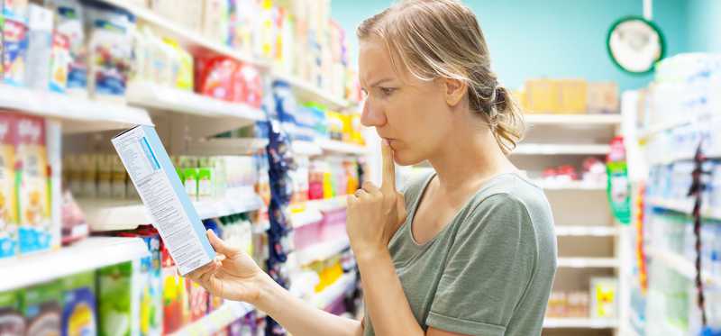 Woman reading the label on a cereal box.