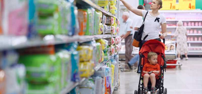 A woman shopping for diapers in the aisle of a store
