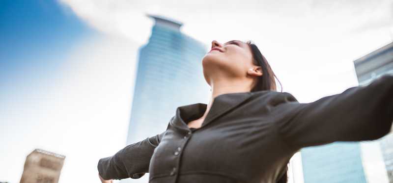 Person spreads arms wide and looks up to sky.