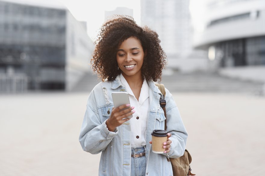 Person looking at phone while walking in city.