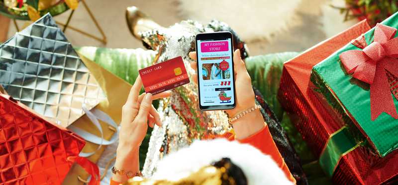 Person using credit card to shop for gifts on smartphone.