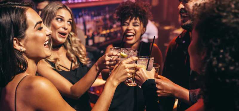 Smiling people holding drinks and making a toast.