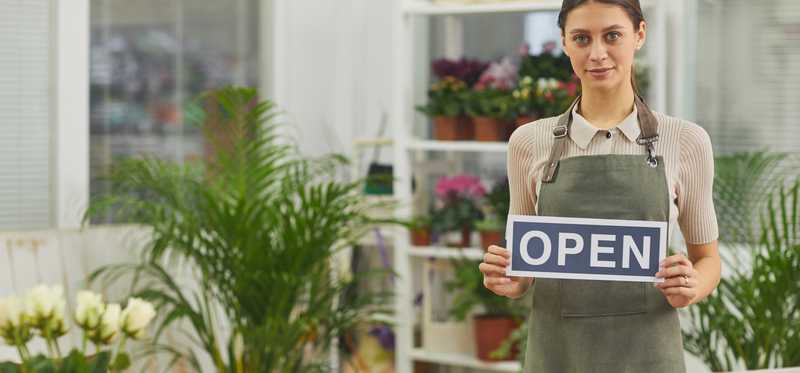 Worker in floral shop holding open sign