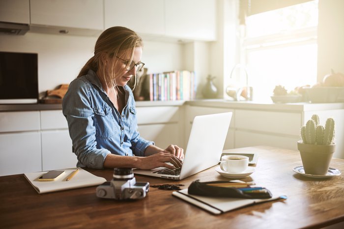 Woman typing on laptop on kitchen counter