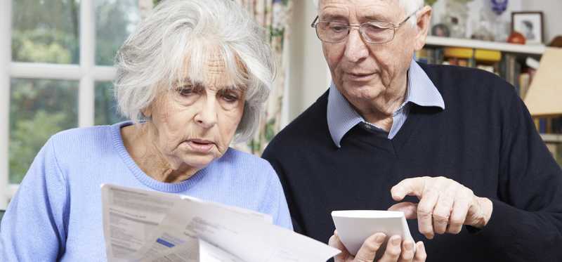 Two worried people using calculator and looking at bill.