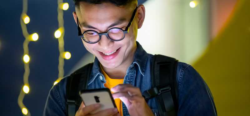Person smiling and looking at smartphone.
