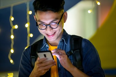 Person smiling and looking at smartphone.