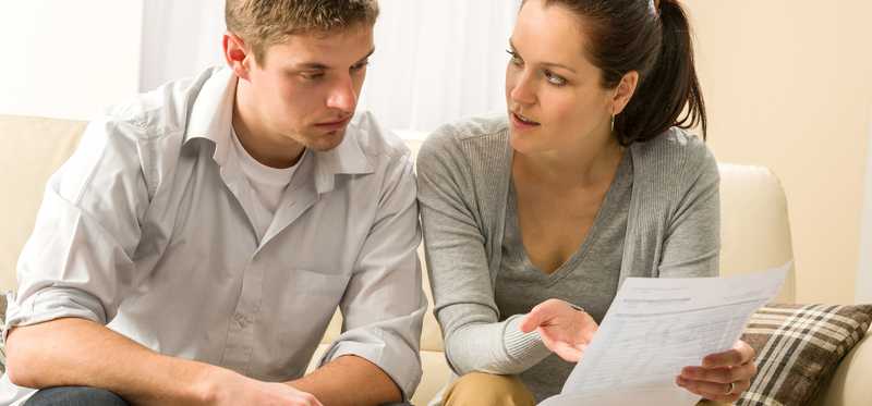 Two people discussing financial documents and looking worried.