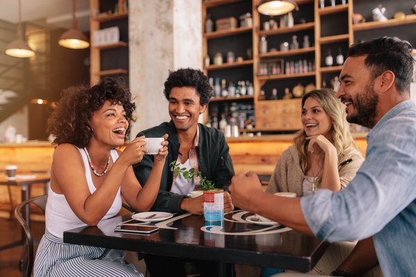 Friends laughing and enjoying a cup of coffee at a coffeeshop.