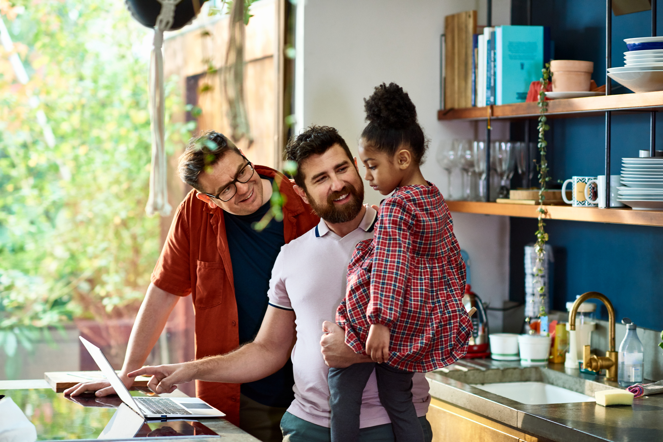 Two adults and a child with a laptop in a kitchen. Two adults and a child with a laptop in a kitchen.