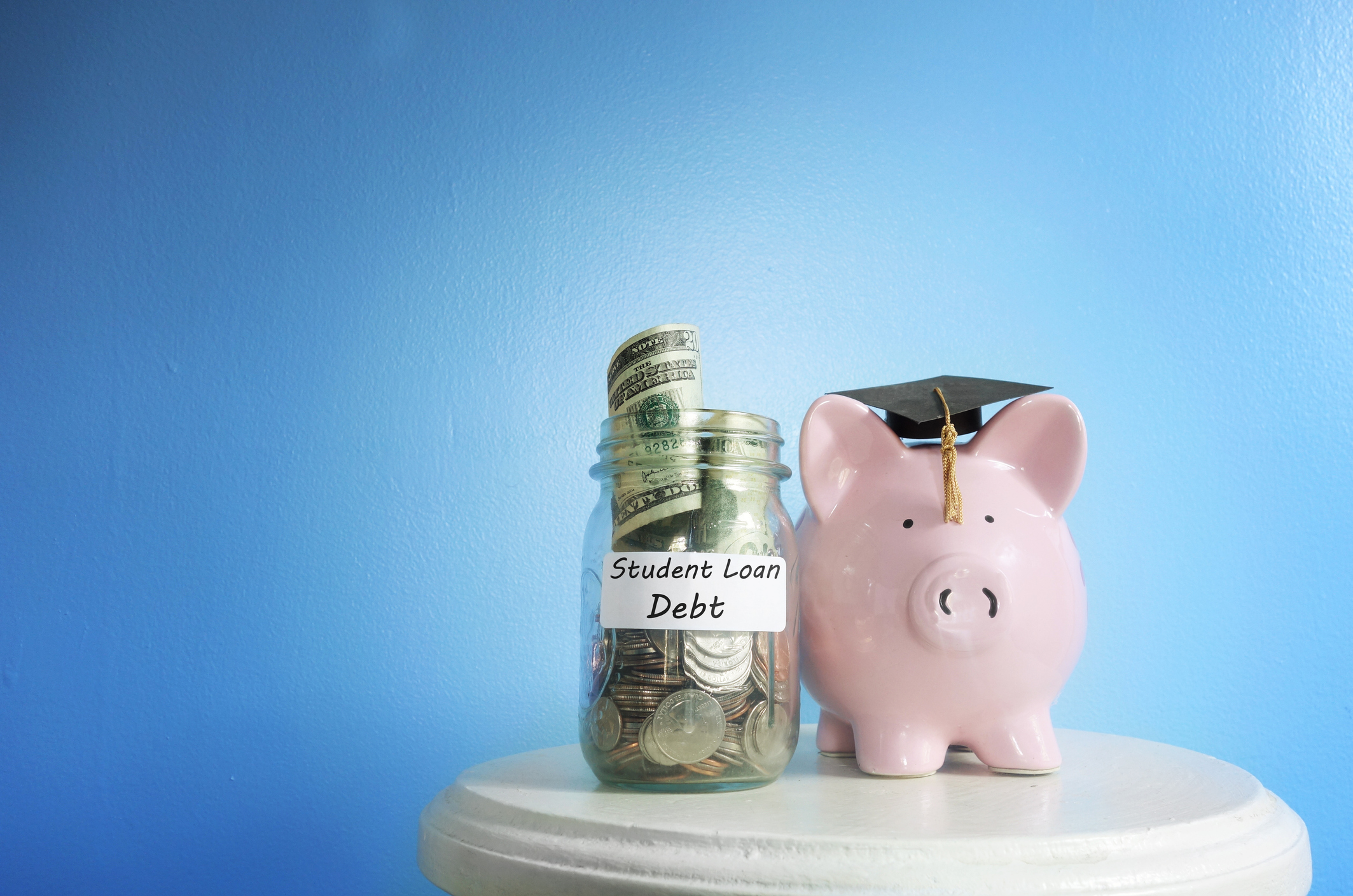 Student loan debt A piggy bank next to a jar full of money labeled Student Loan Debt.