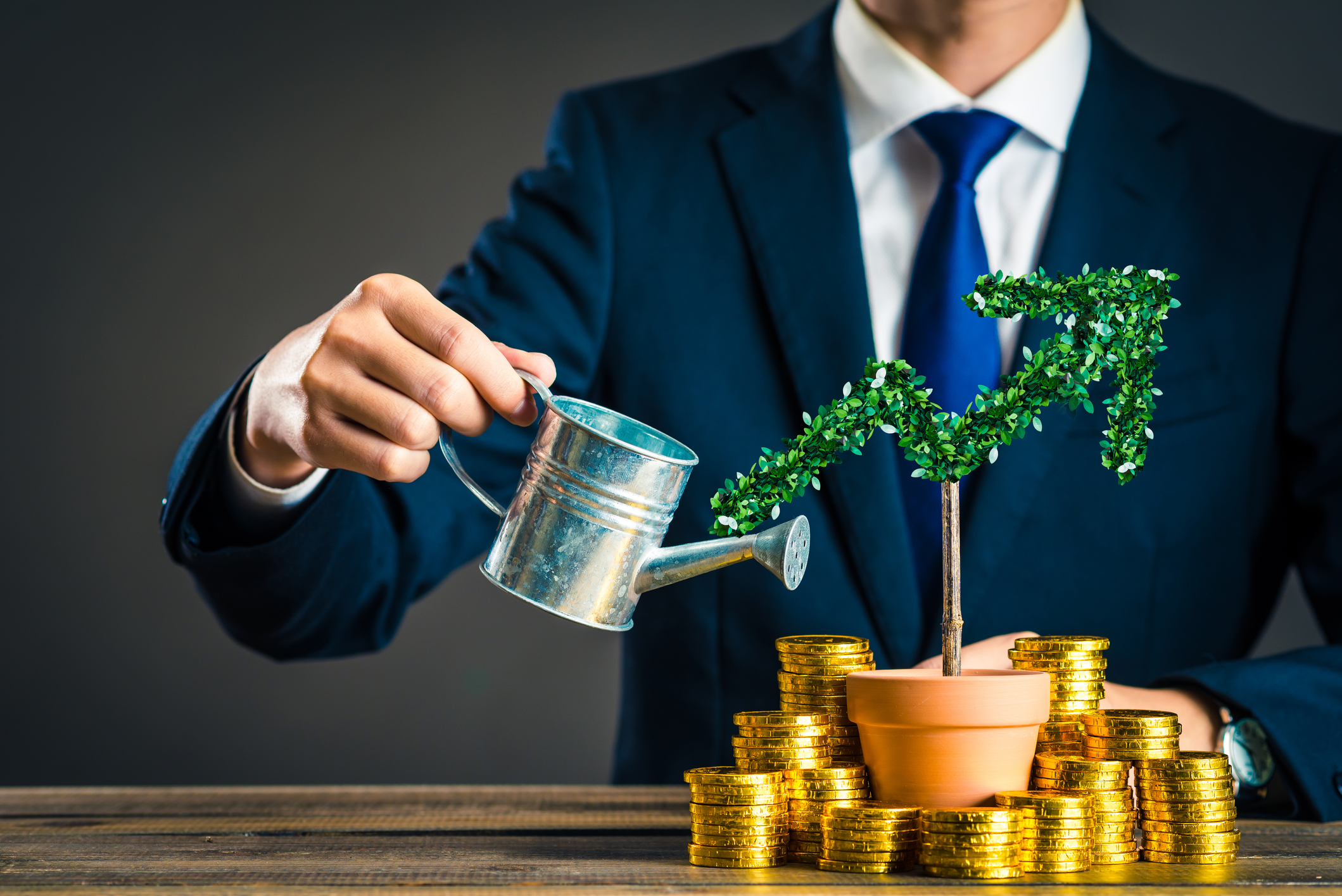 Man watering a plant that looks like a line going up with coins around the pot