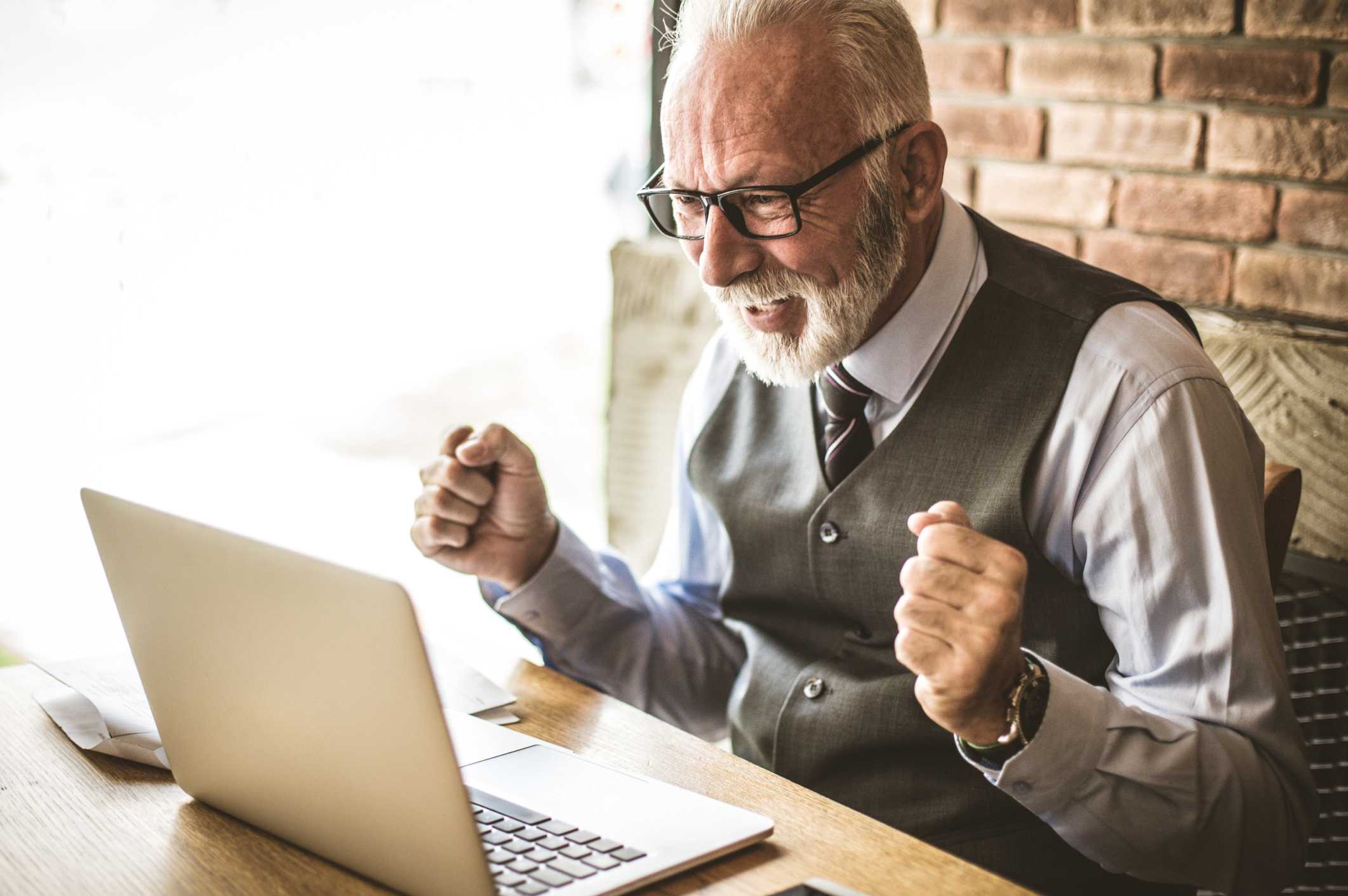 Happy mature person in vest looking at laptop