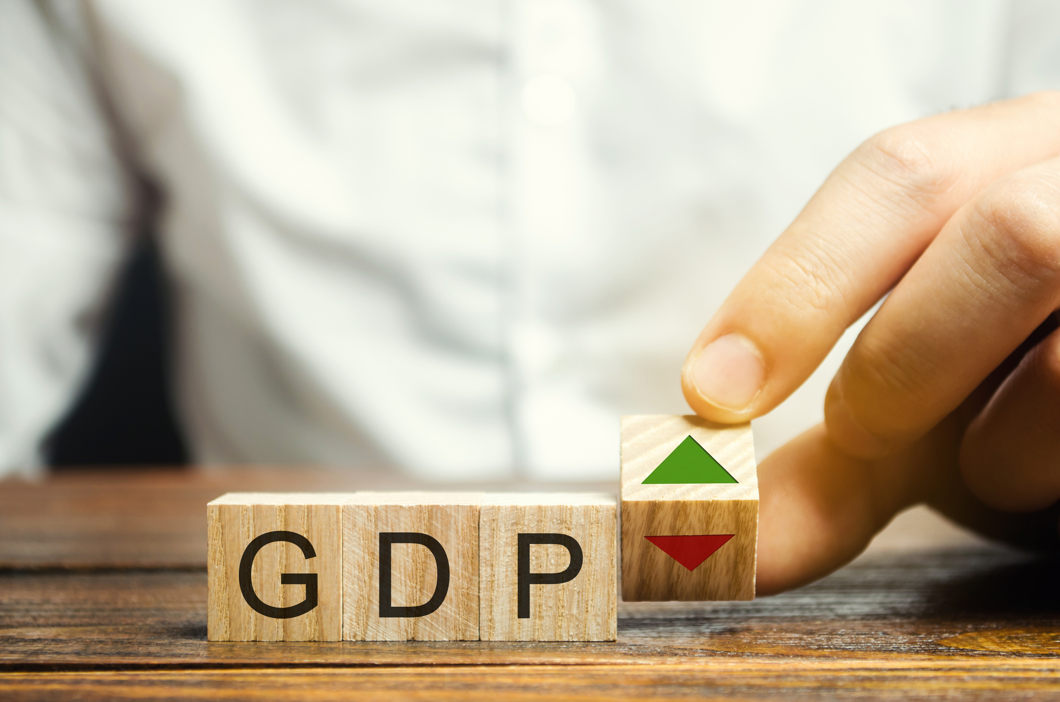 Person sitting in front of blocks spelling GDP.