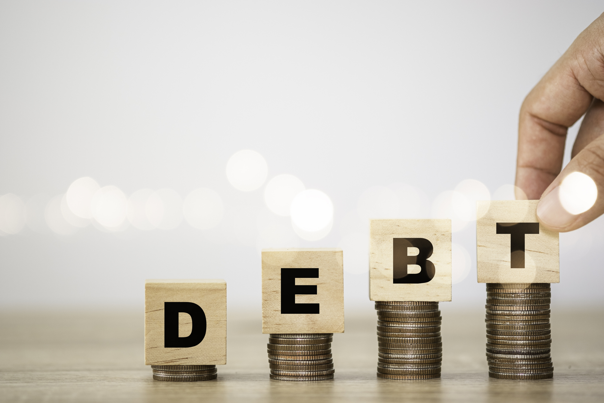 Rising stacks of coins with blocks atop spelling out DEBT Rising stacks of coins with blocks atop spelling out Debt.