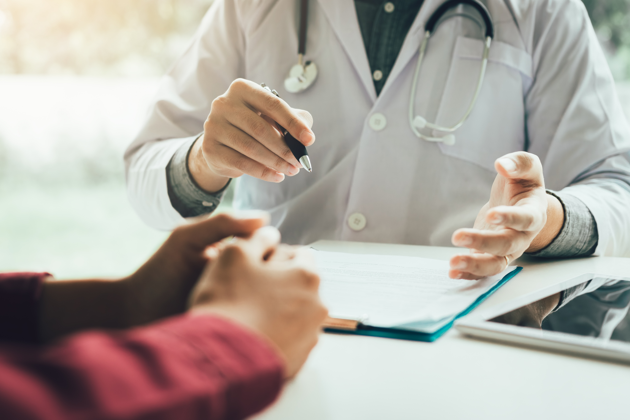 Doctor with a chart in from of him sits across from an individual. Doctor with a chart in from of him sits across from an individual.