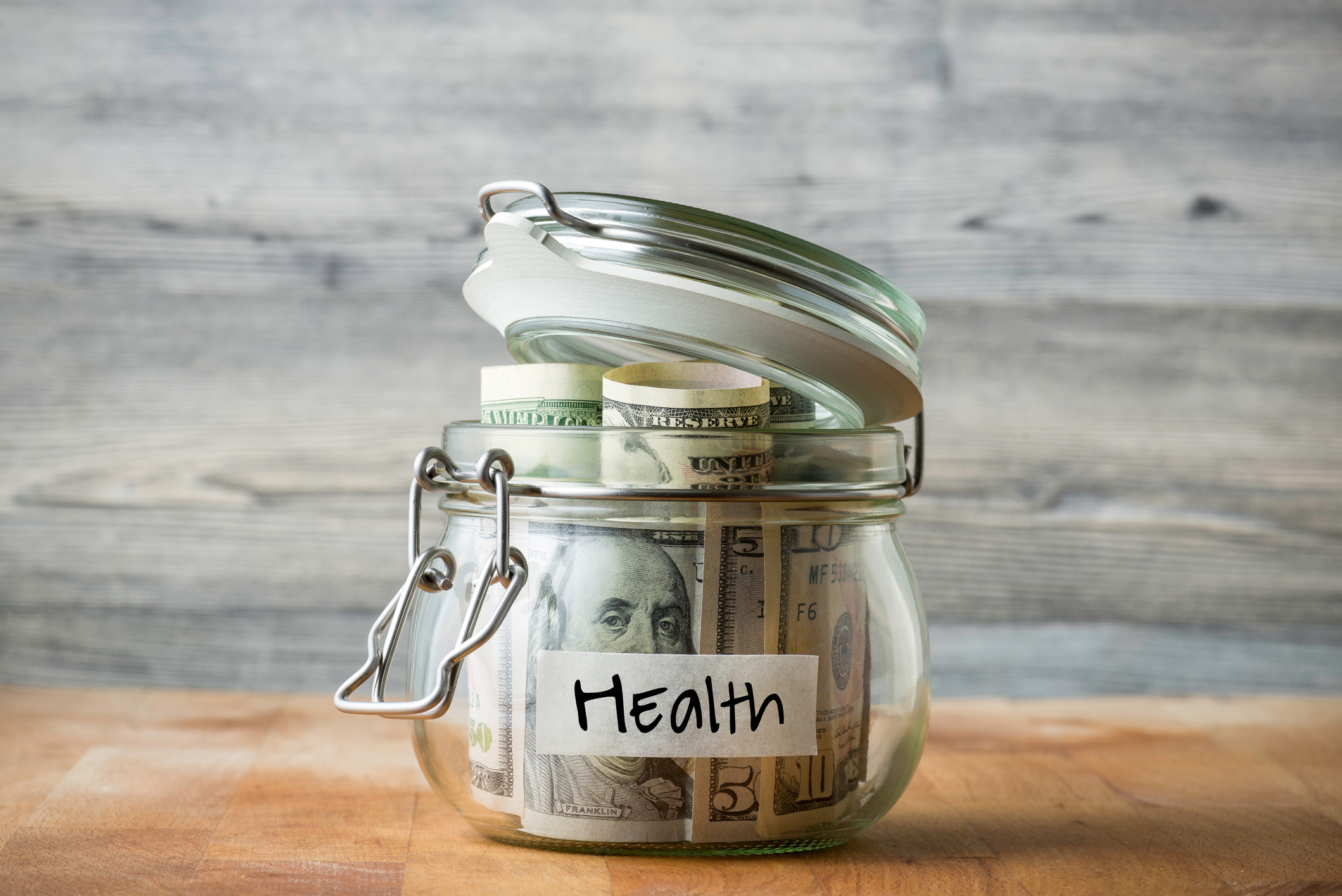 A glass money jar labeled health that's full of cash. A glass money jar labeled health that's full of cash.