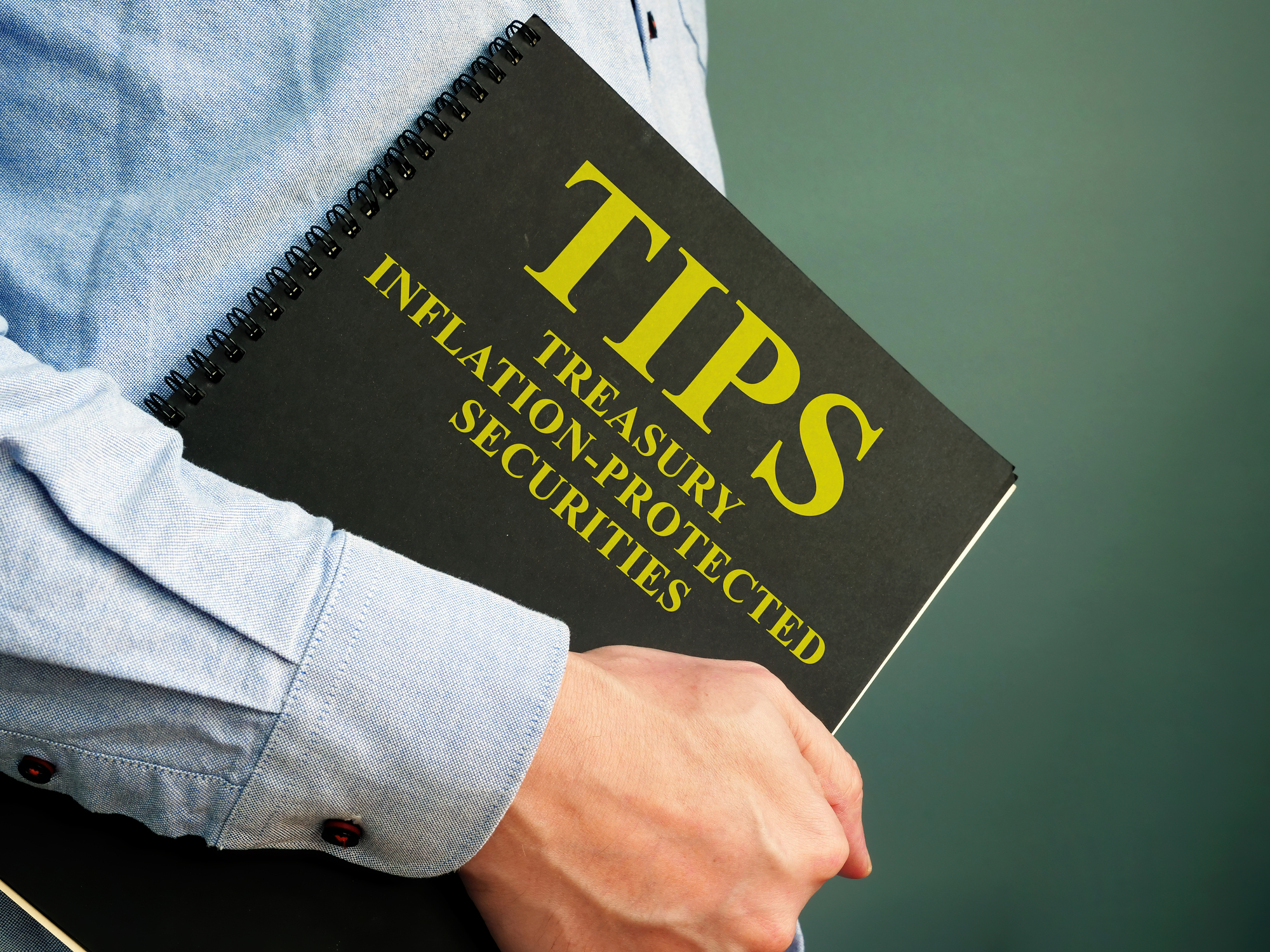 Person holding notebook labeled TIPS Person holding notebook labeled TIPS, Treasury Inflation-Protected Securities.