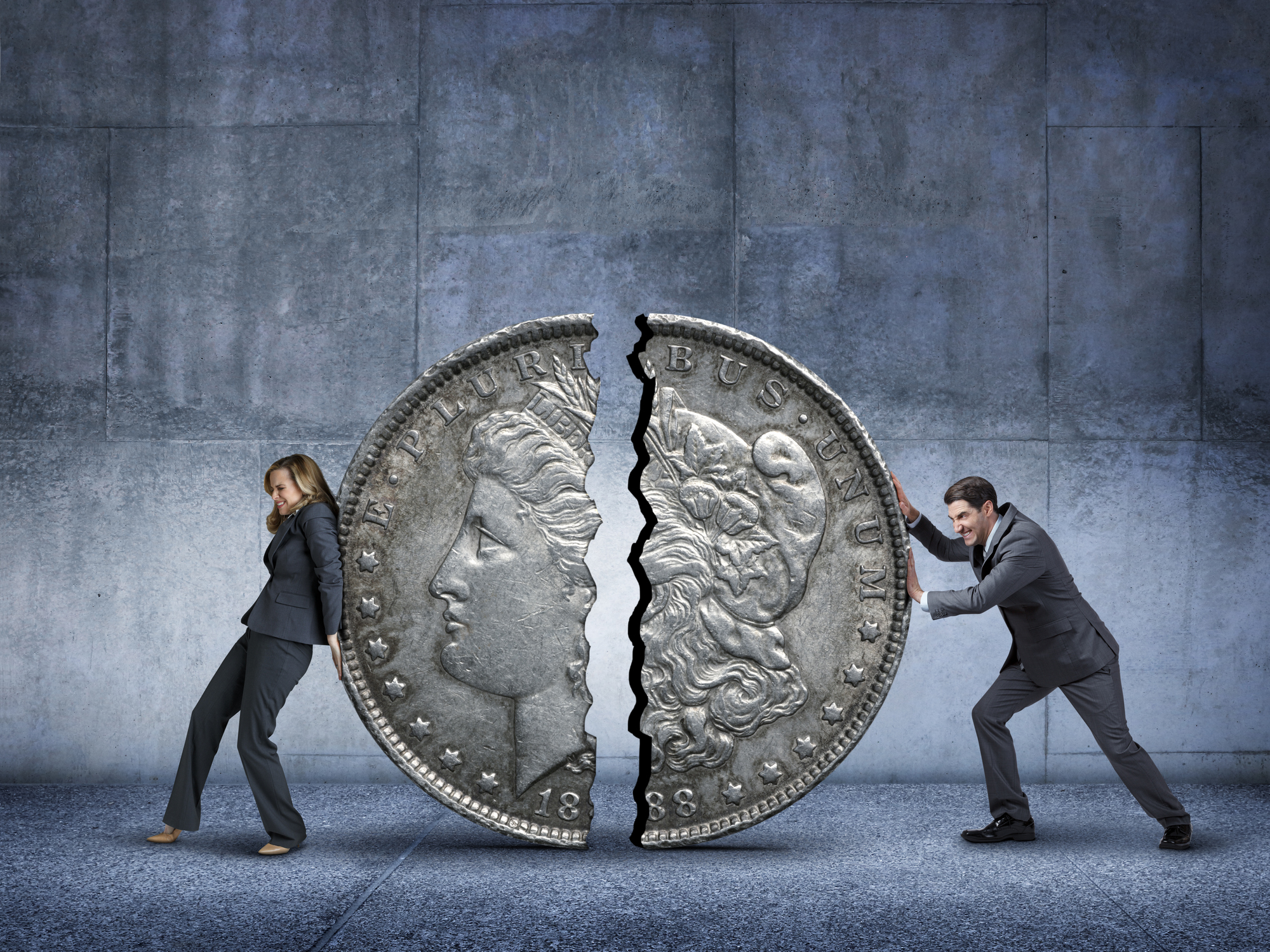 Woman and man pushing a coin split in half back together Woman and man pushing a coin split in half back together