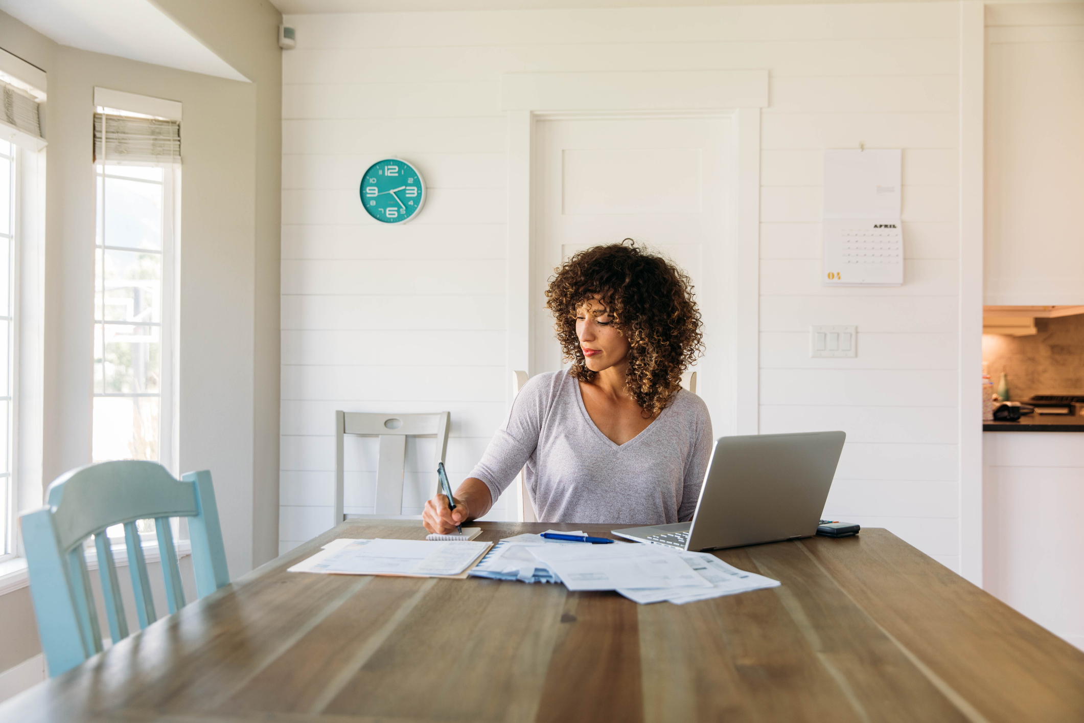 9-paying-taxes.jpg Person sits at dining table with paperwork and laptop.