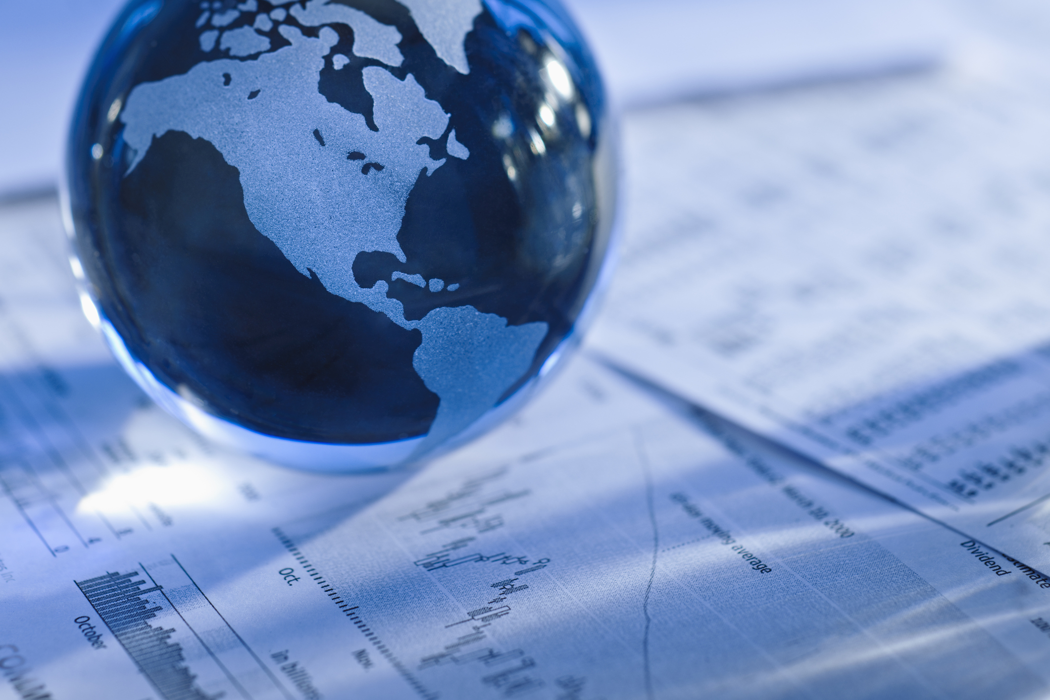 miniature globe resting on financial paperwork A miniature globe rests on some financial paperwork.