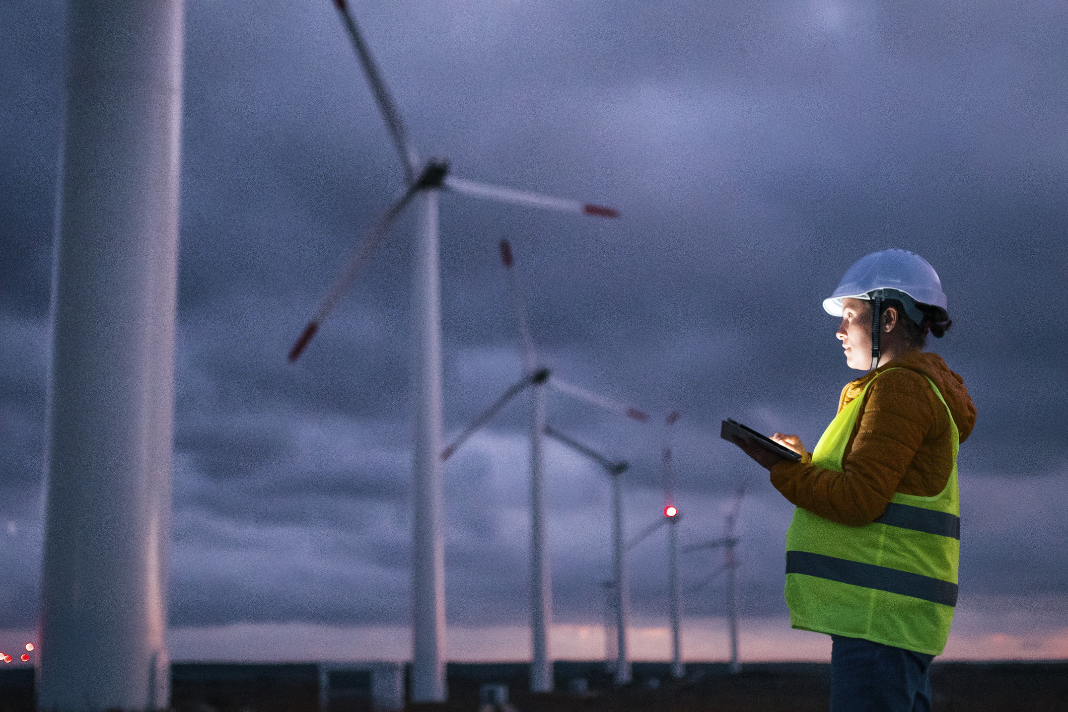 A person holding a tablet looking at wind turbines. A person holding a tablet looking at wind turbines.