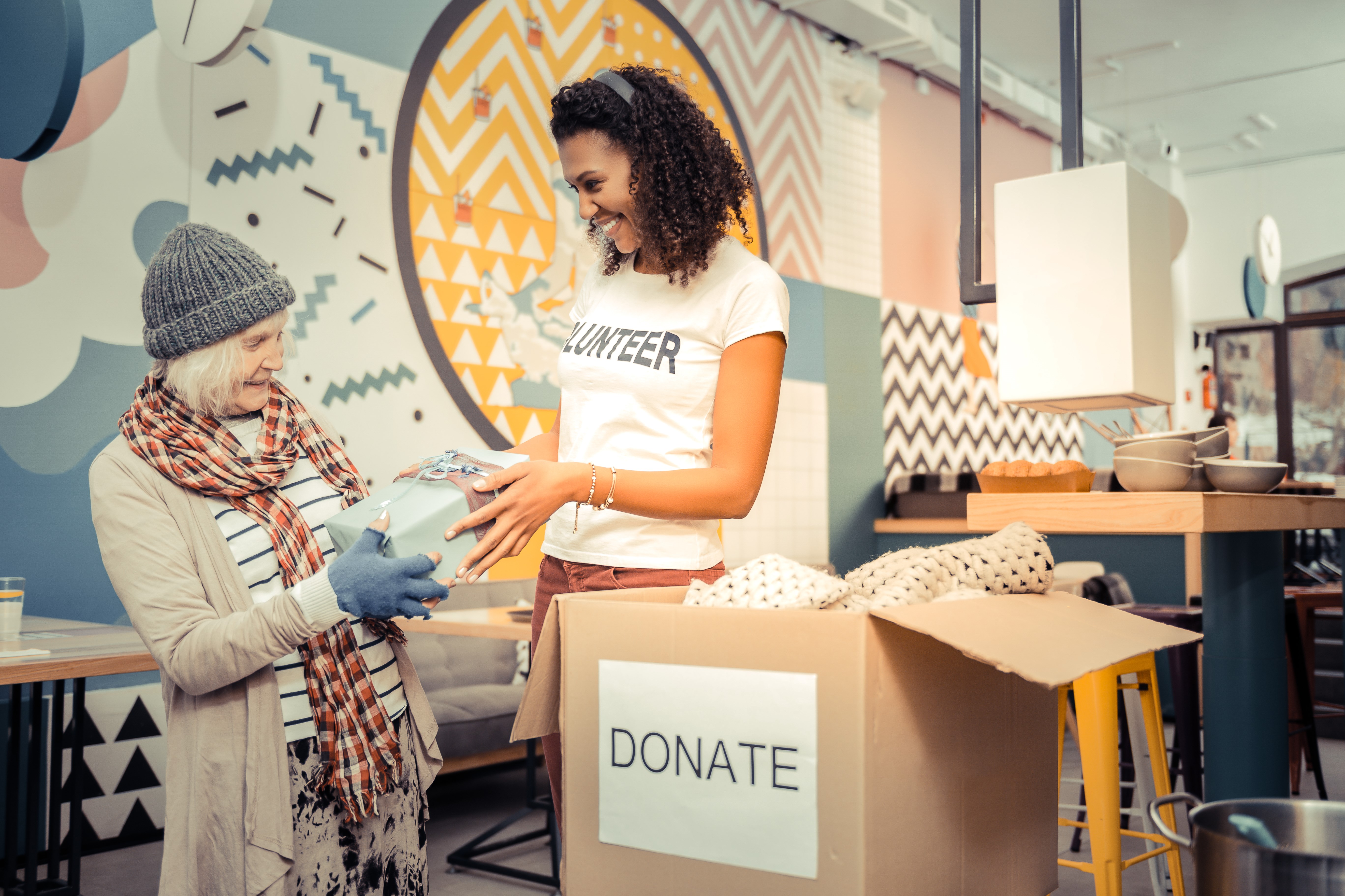 Charity volunteer assisting a client near donation box