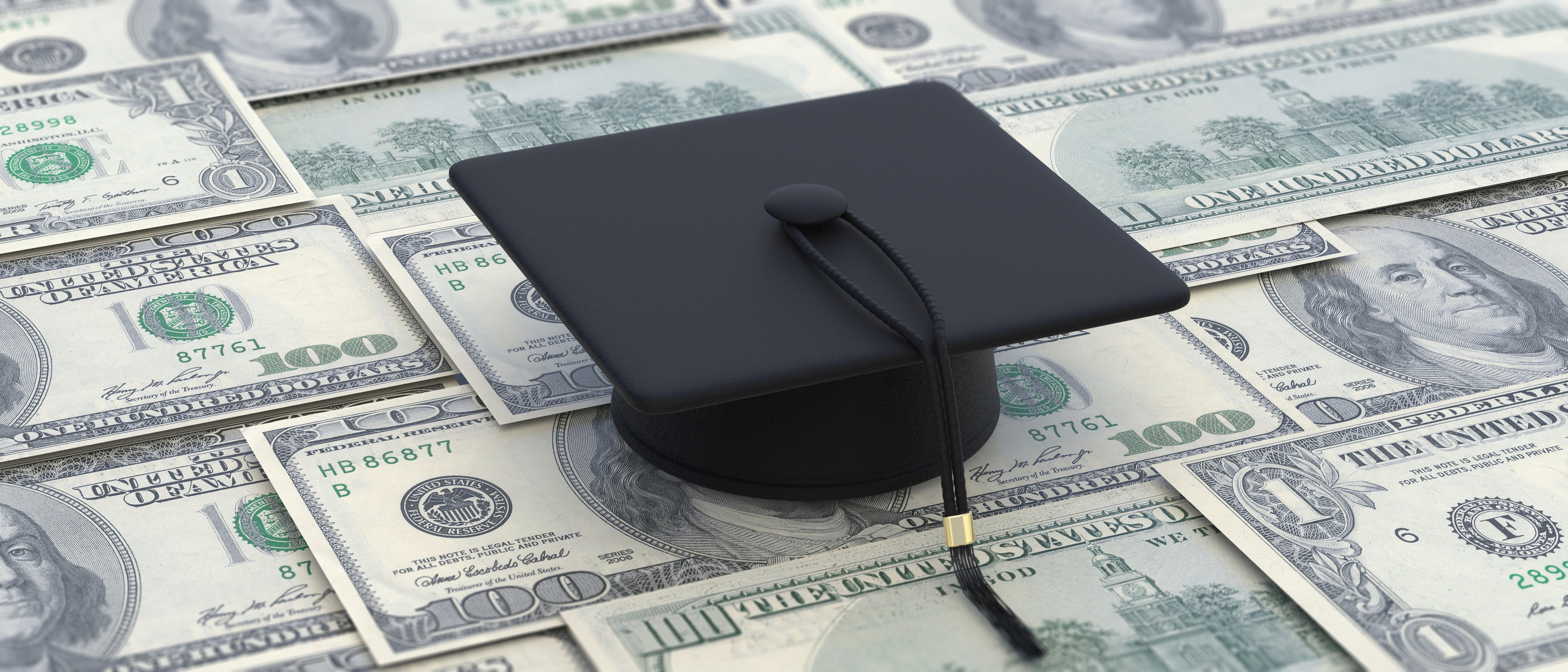 College cost, student loan, scholarship. Graduate cap on dollar banknotes Graduate cap lying atop one-hundred-dollar banknotes