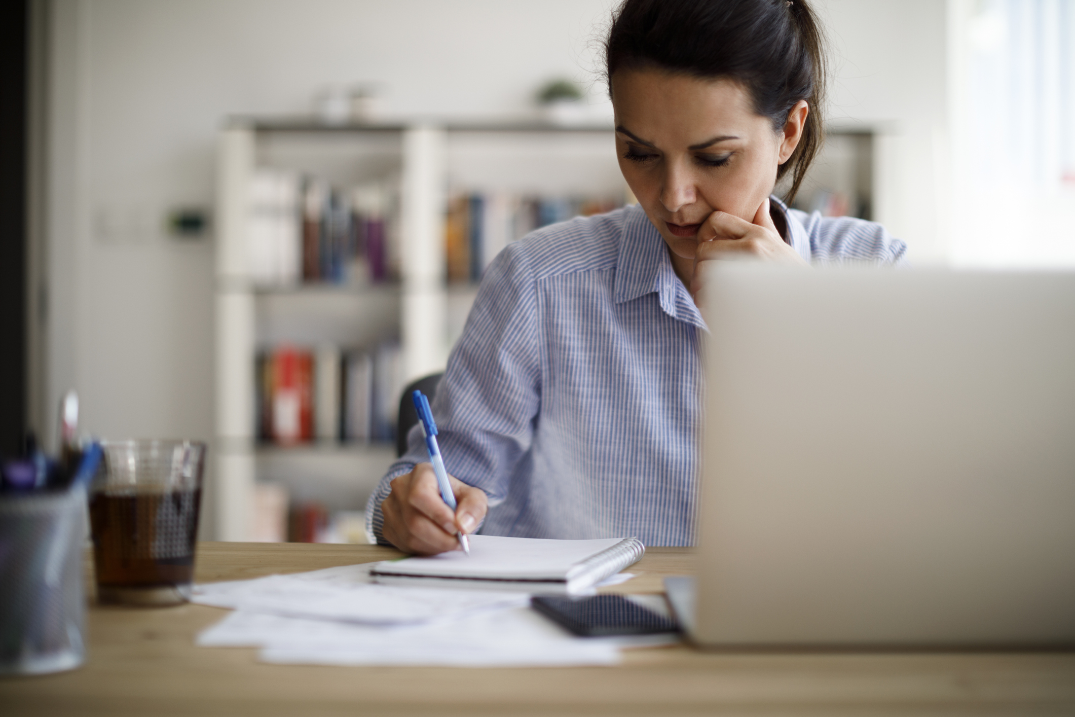 Woman sitting at table with computer and paying bills Woman sitting at table with computer and paying bills
