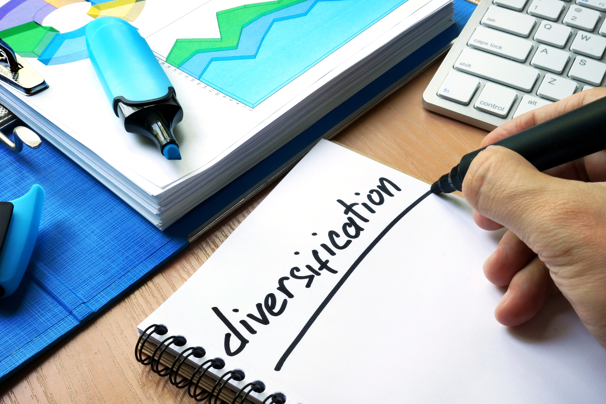 Person writing the word Diversification on a notepad in black marker