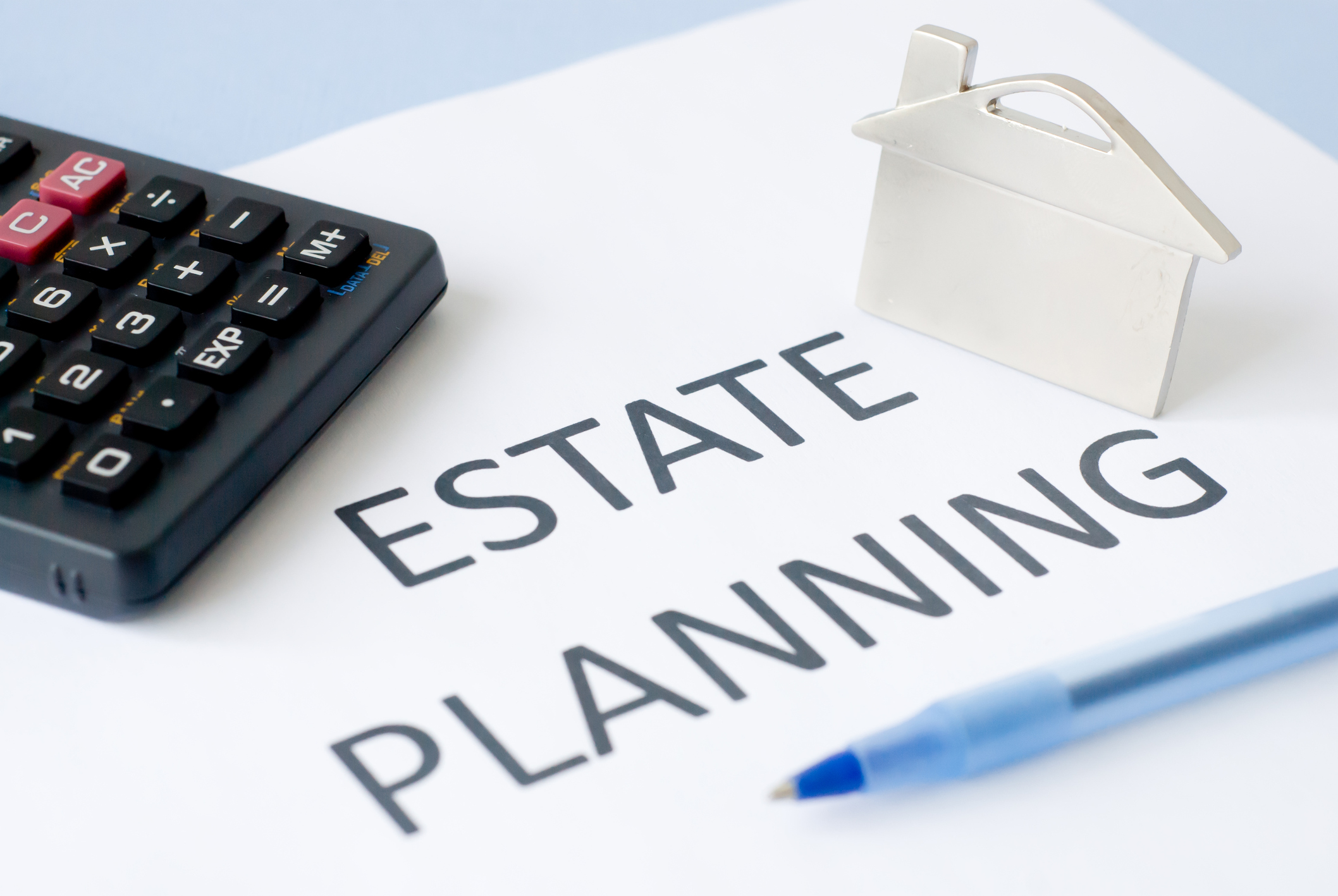 estate planning Estate Planning written on paper with calculator and small metal house on top.