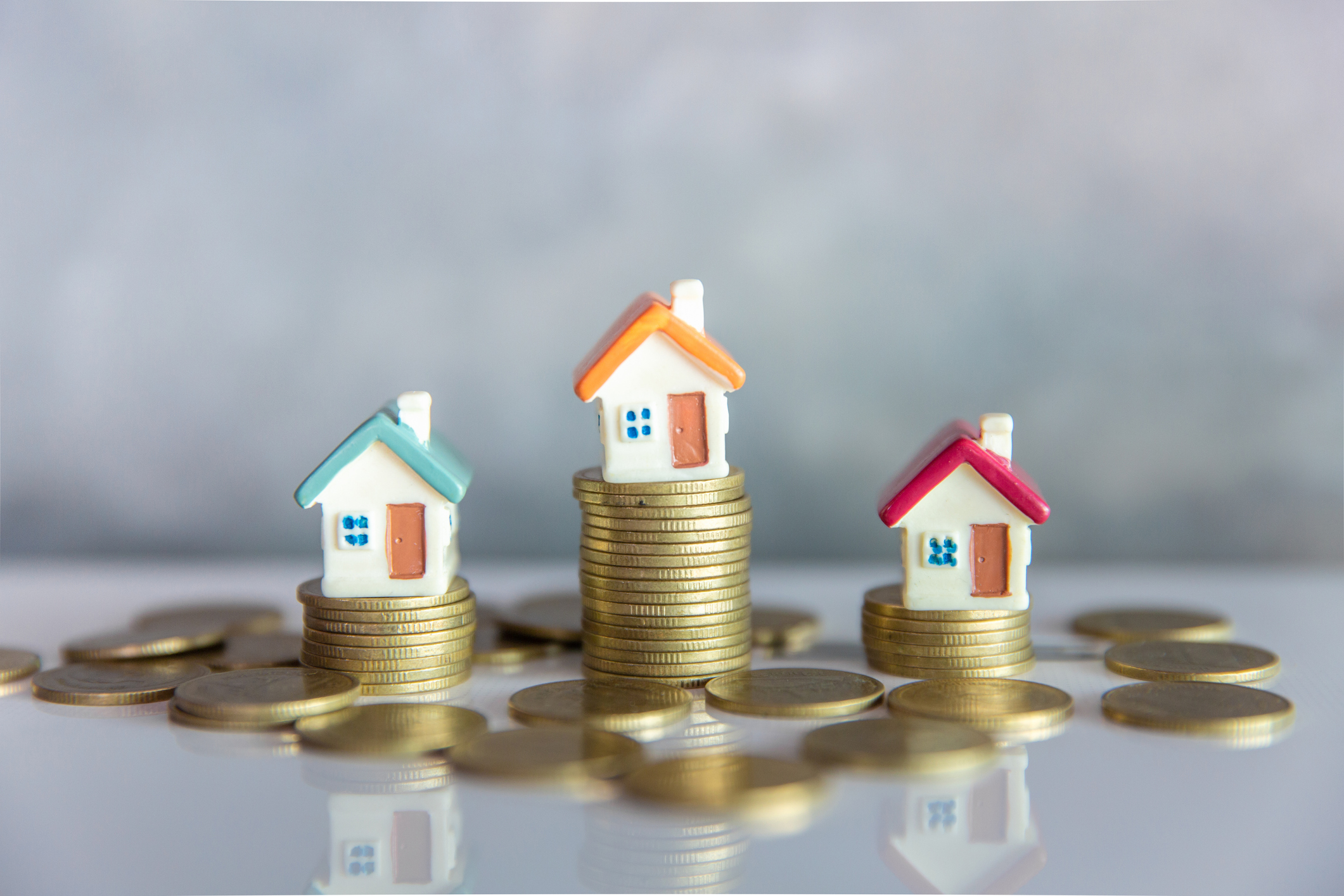after_repair_value_real_estate Miniature houses on top of stacks of coins.