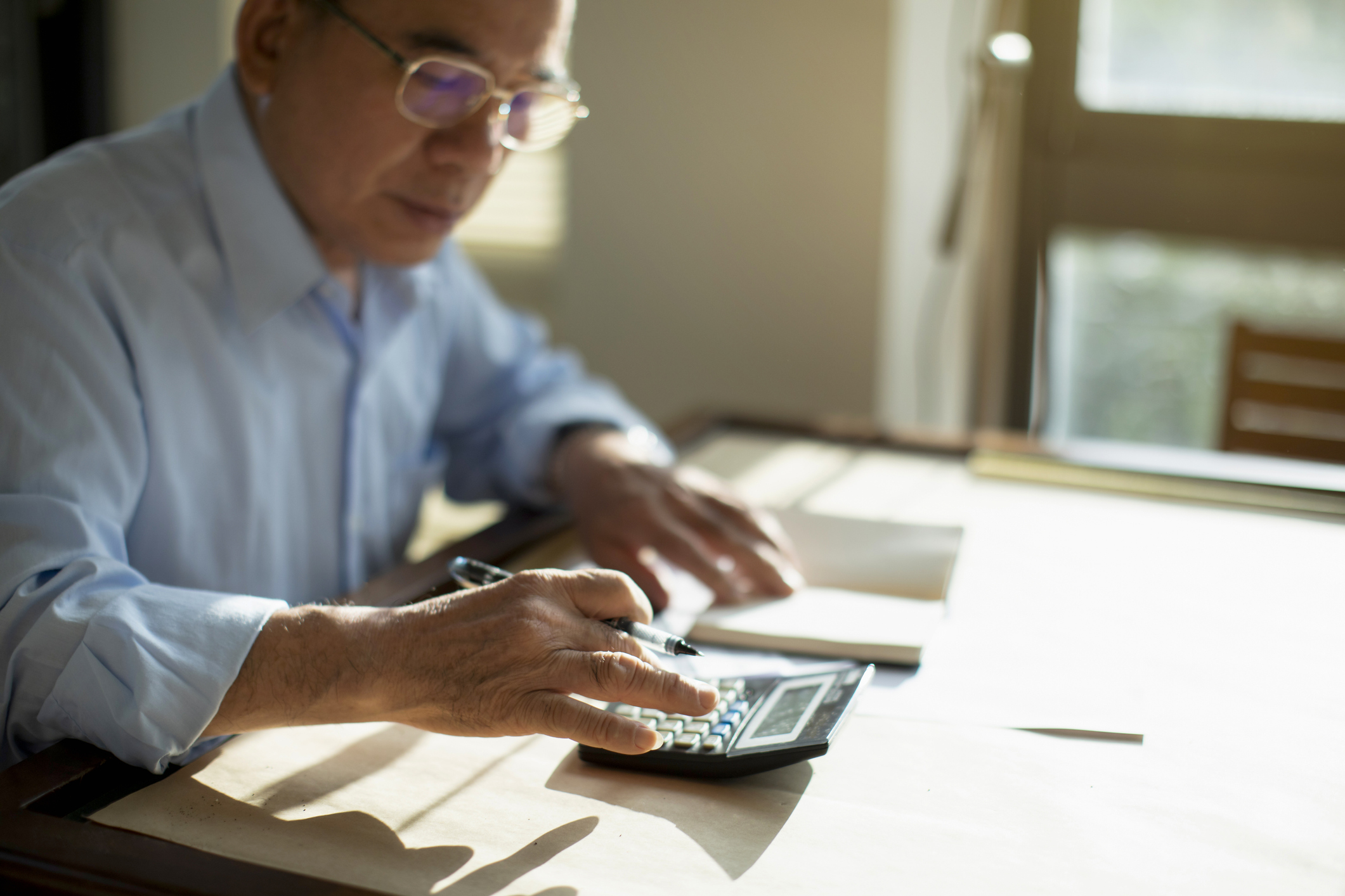 how_to_value_a_reit_person_using_calculator Person sitting at table and calculating finances.