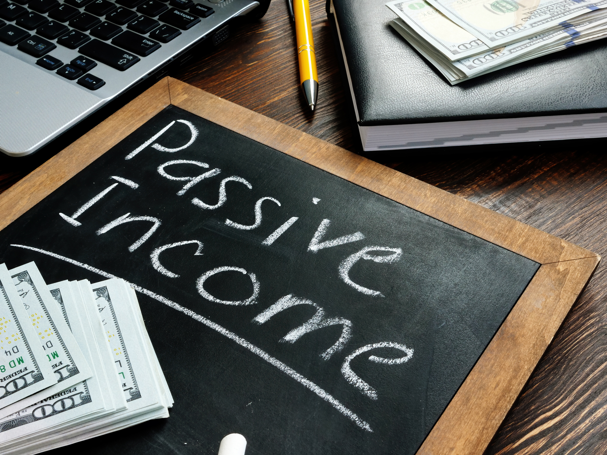 Passive income Passive Income written on a chalkboard with money lying on top.