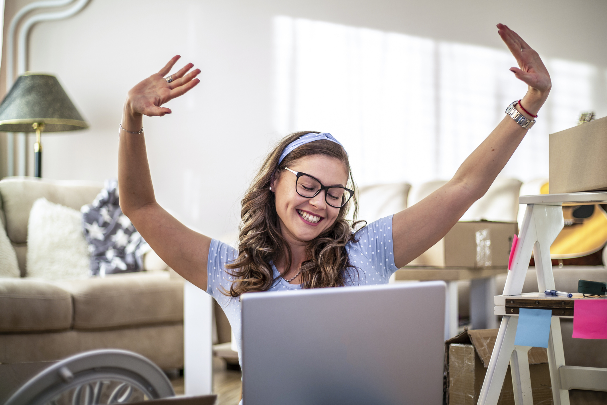 GettyImages-1304761625.jpg Person in front of computer is excited and smiling with hands in air.