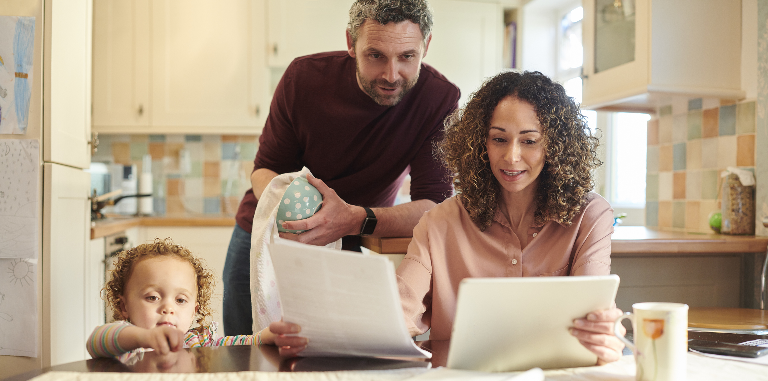 family looking at papers at their kitchen table Family looking at paperwork at their kitchen table.