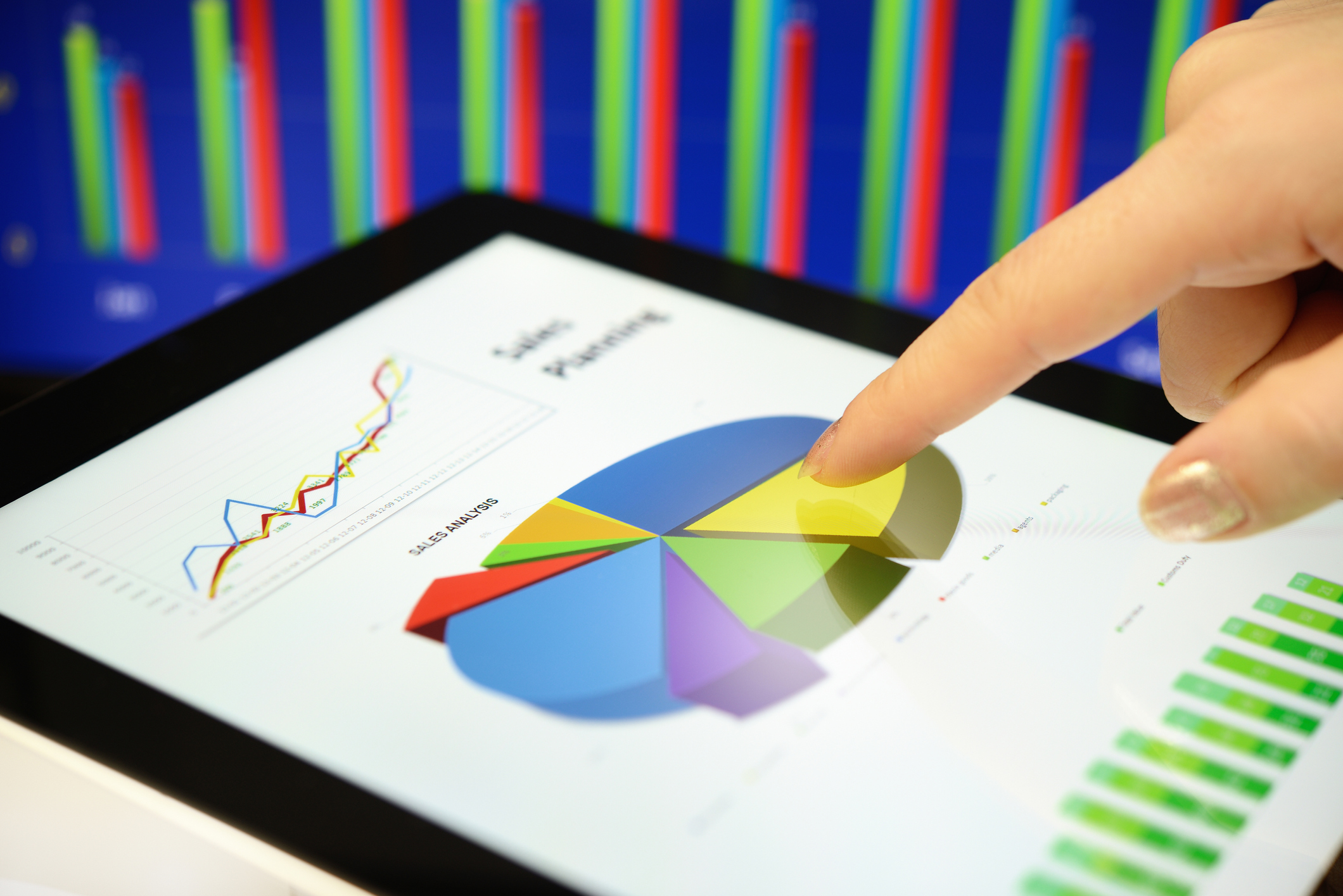 portfolio planning Hand pointing to a pie chart on a tablet screen.
