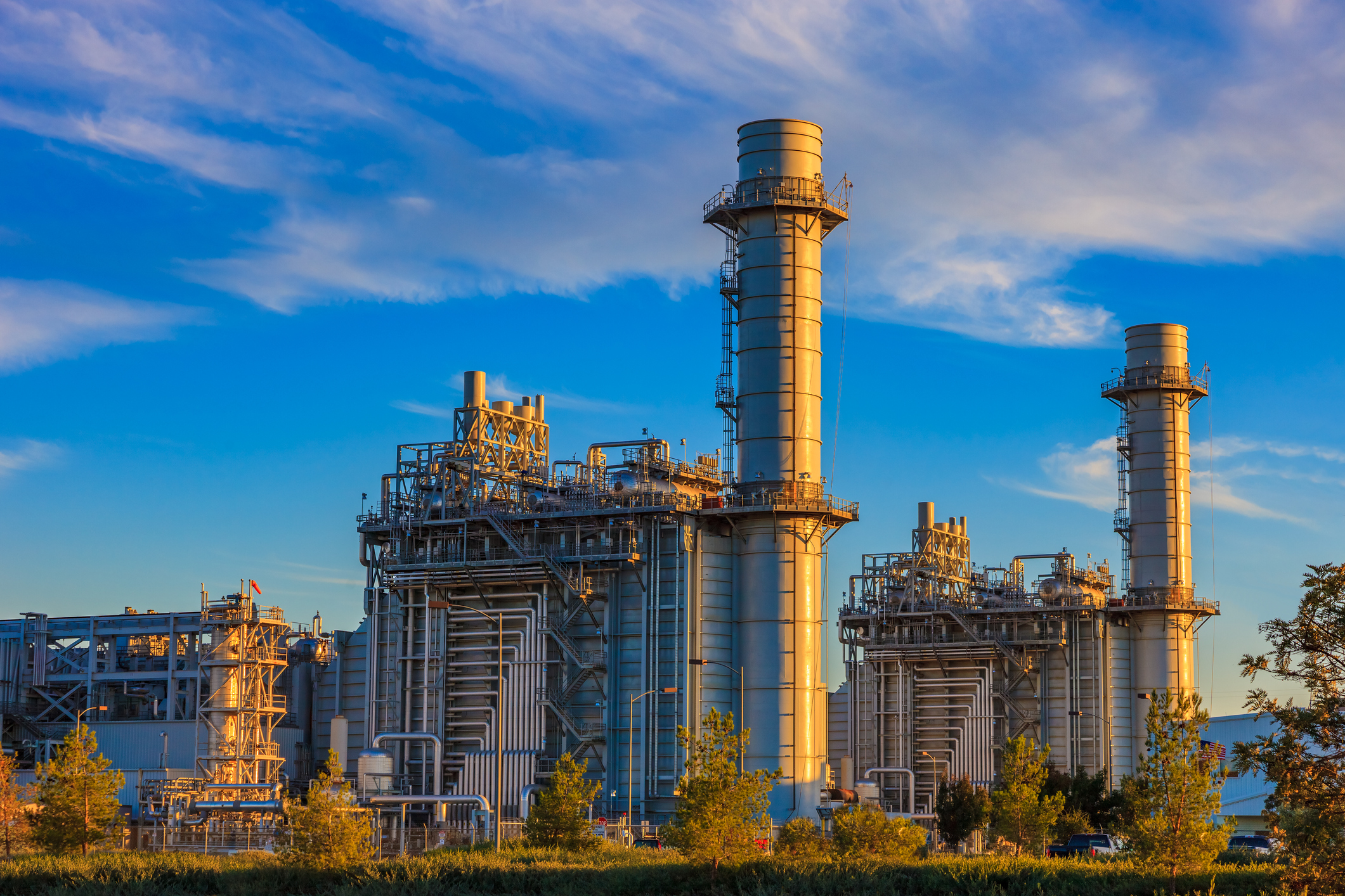 Natural_gas_power_plant Natural gas-fired turbine power plant with its cooling towers rising into a cloud-filled blue sky.