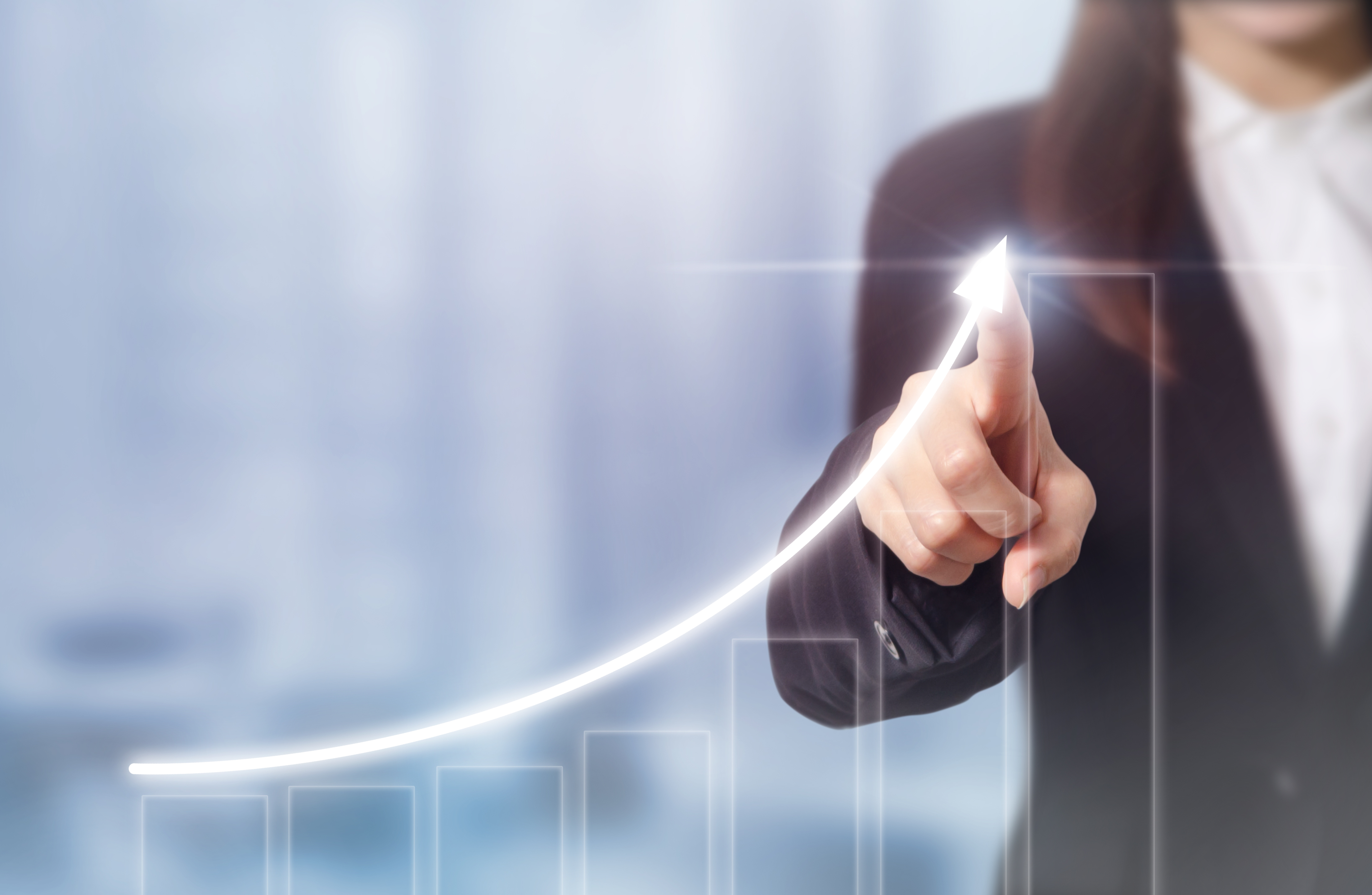 upward growth trend chart Person points to arrow trending up on bar graph.