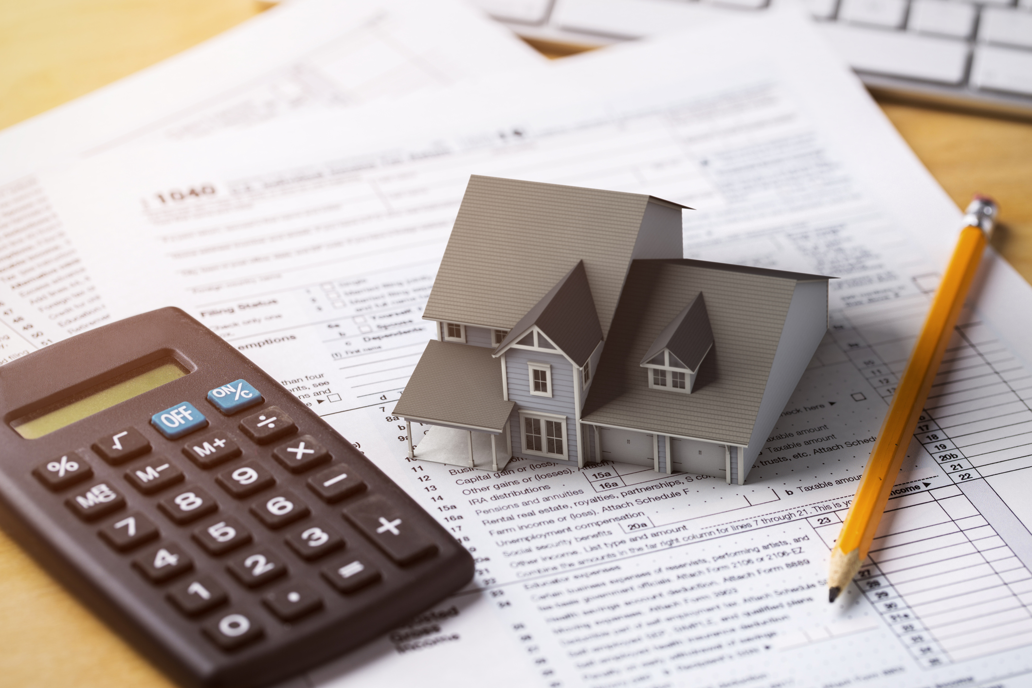 House on top of tax forms with calculator and pencil.jpg Miniature model house on top of tax forms with calculator and pencil.