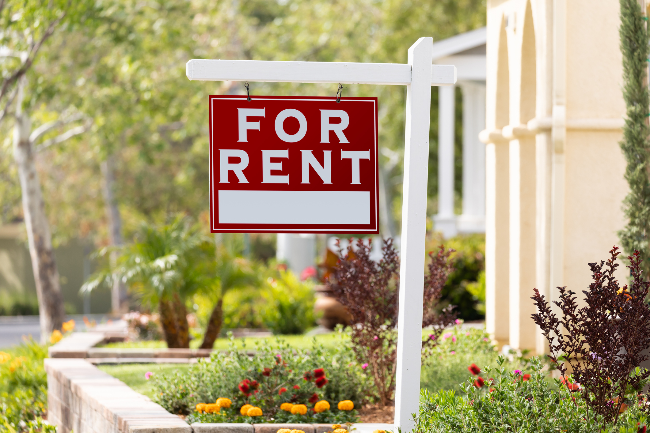 rental property sign A For Rent sign in a flowerbed in front of home.