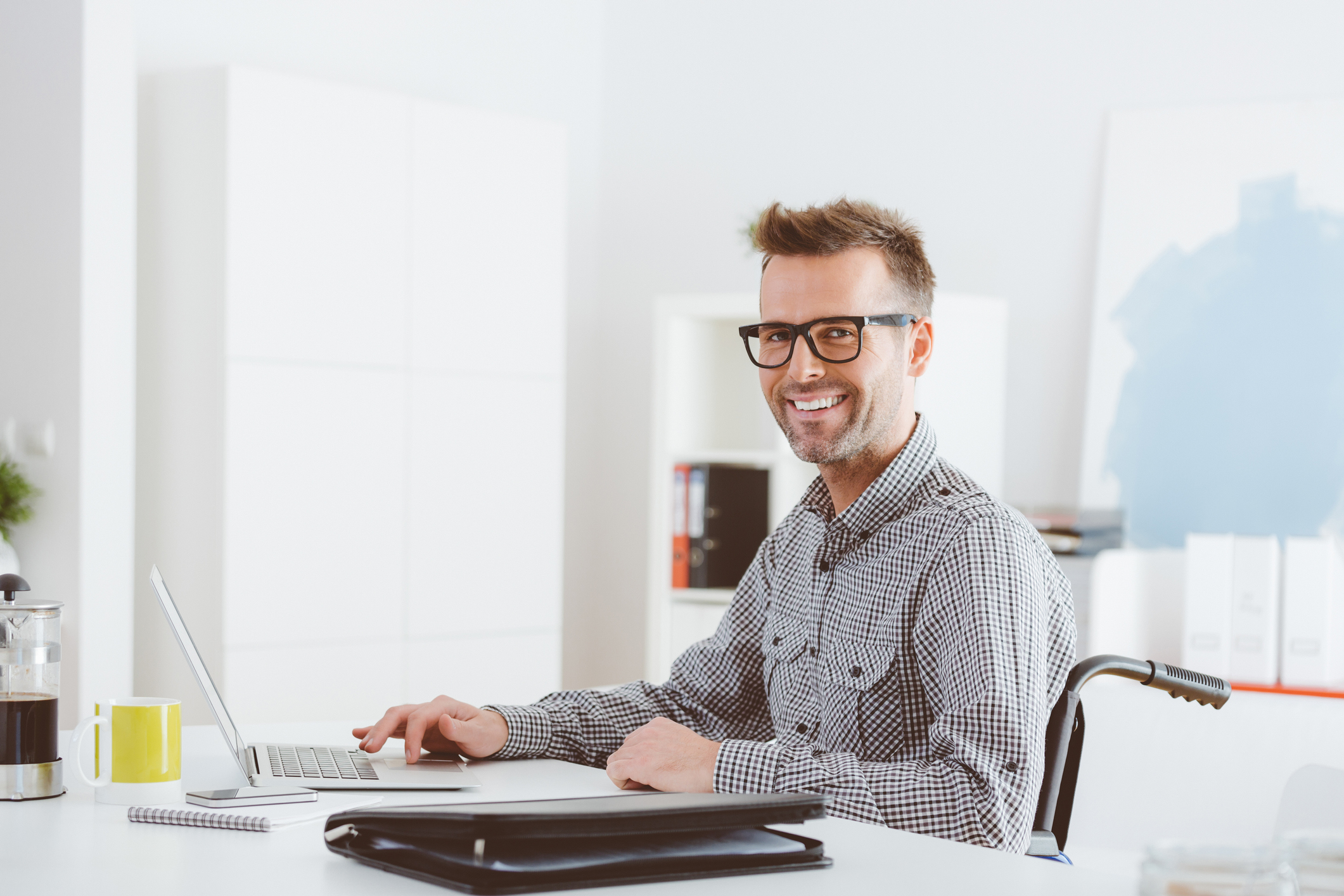 Getty - happy person.jpg A smiling person sitting at a desk.