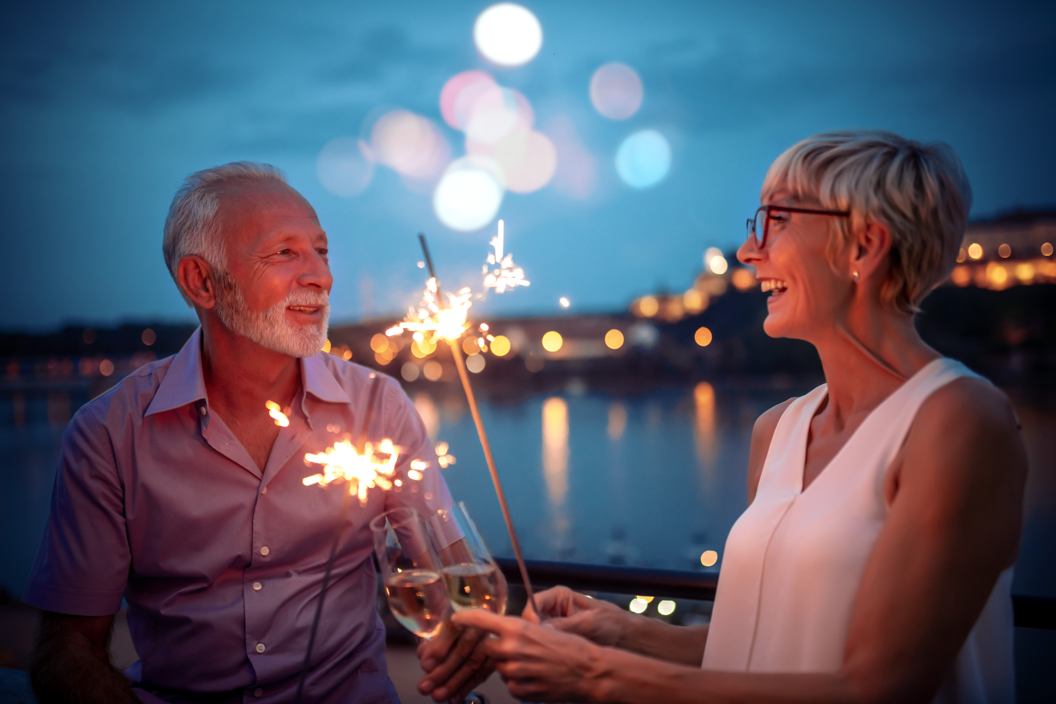 Seniors couple celebrate retire retirement older.jpg Two people celebrating with sparklers at dusk.