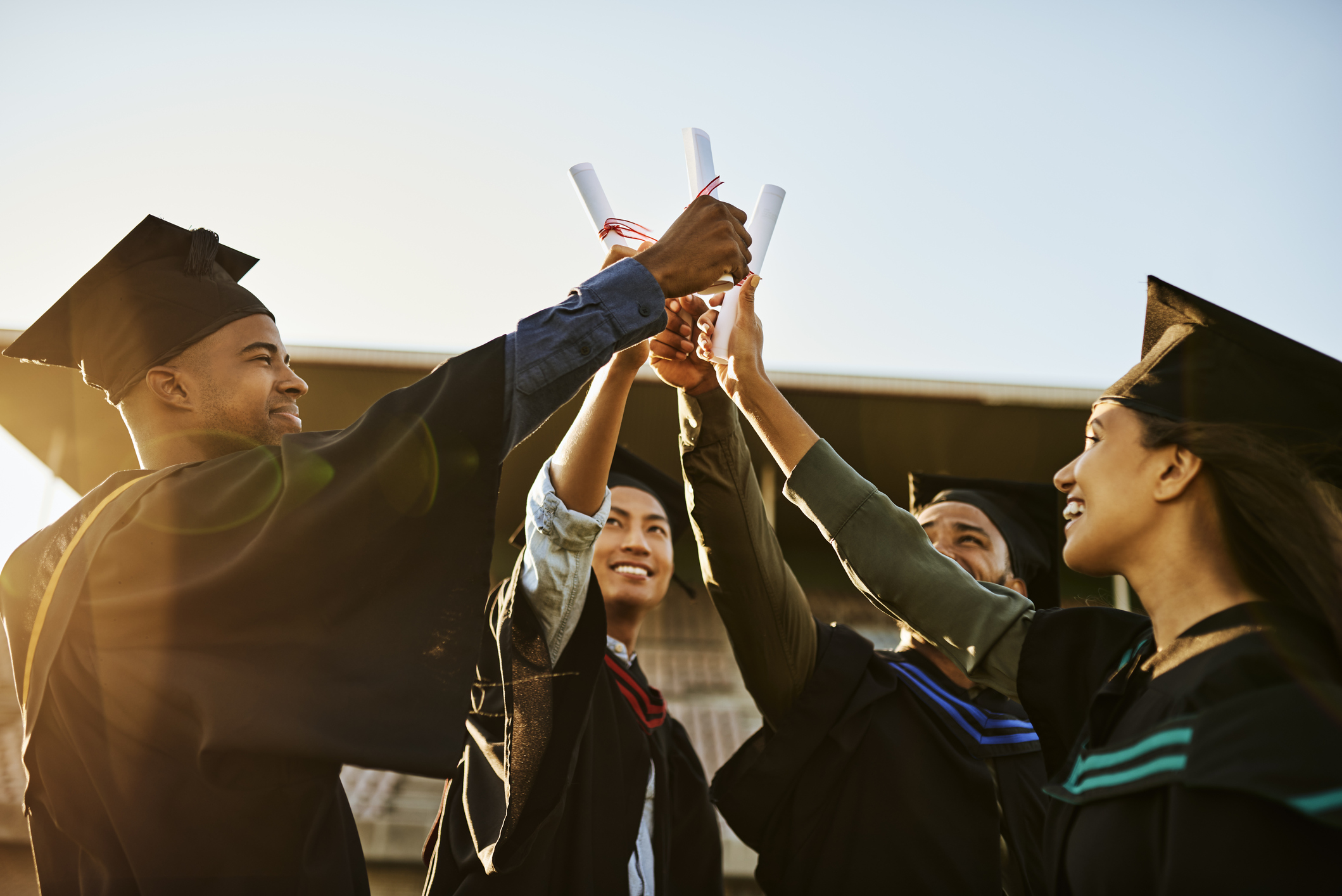 Graduates hold their diplomas up in celebration.
