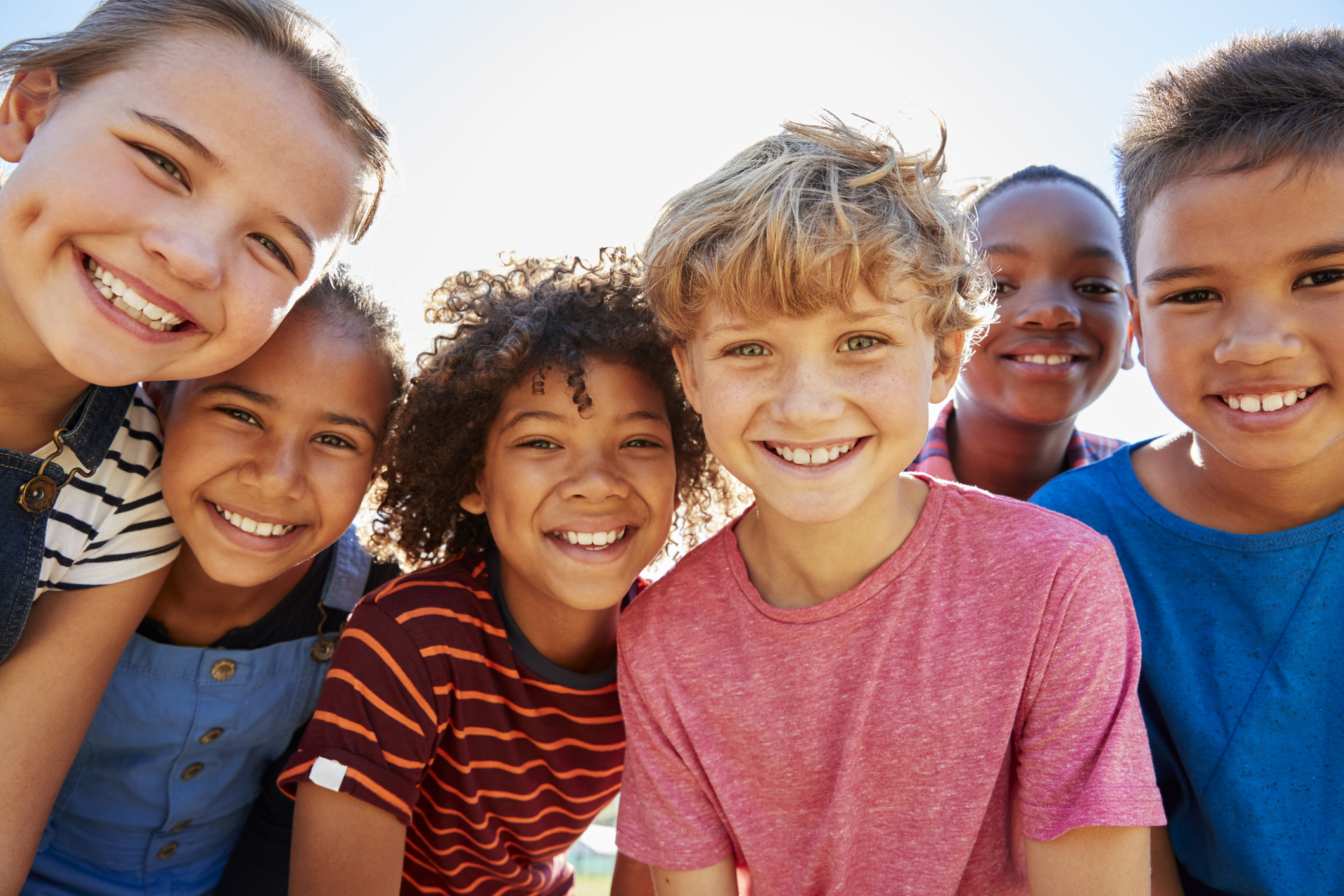 group of children standing shoulder to shoulder and smiling Group of children standing shoulder to shoulder and smiling