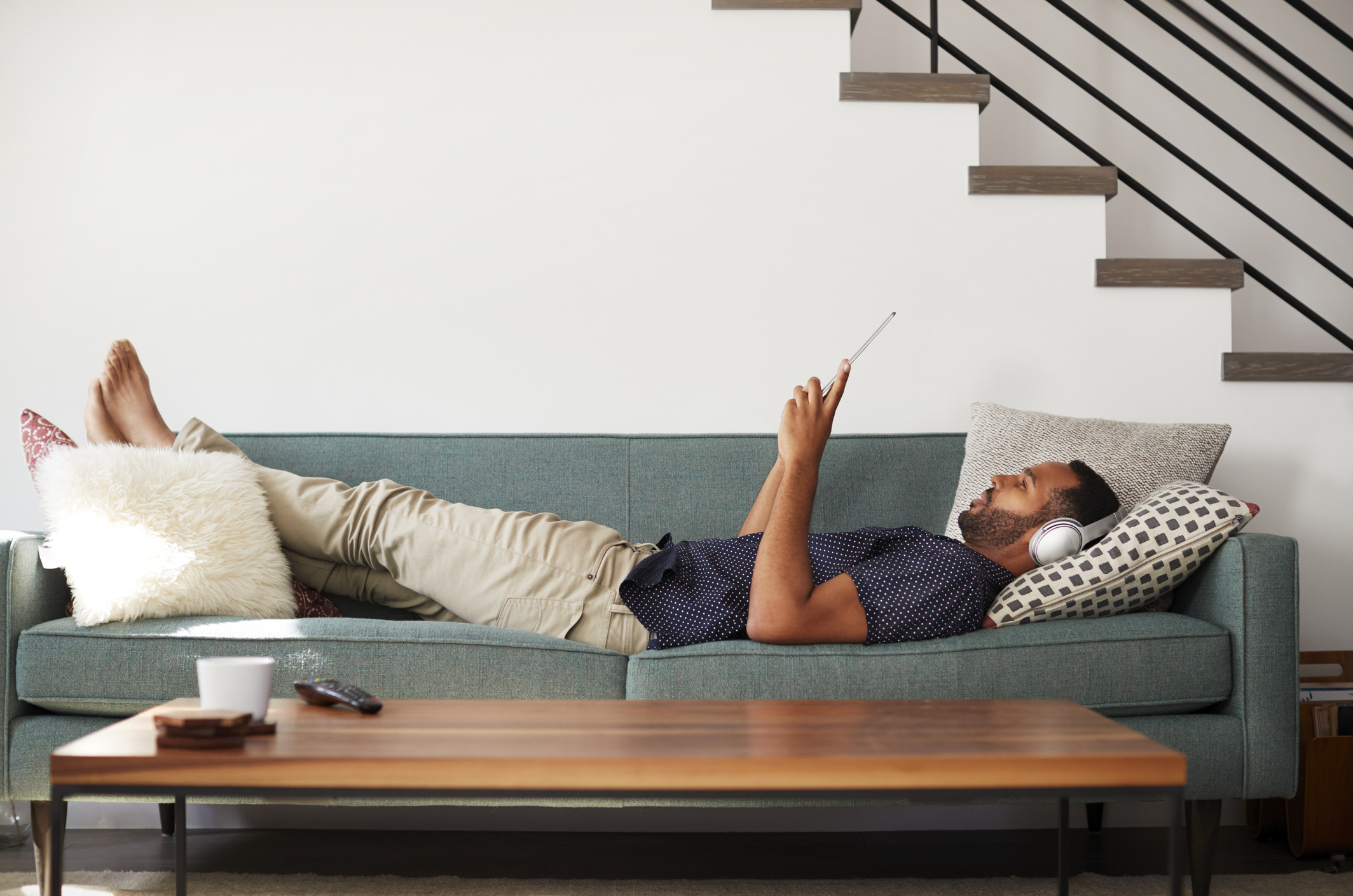Man relaxing on a couch watching something on his smartphone.
