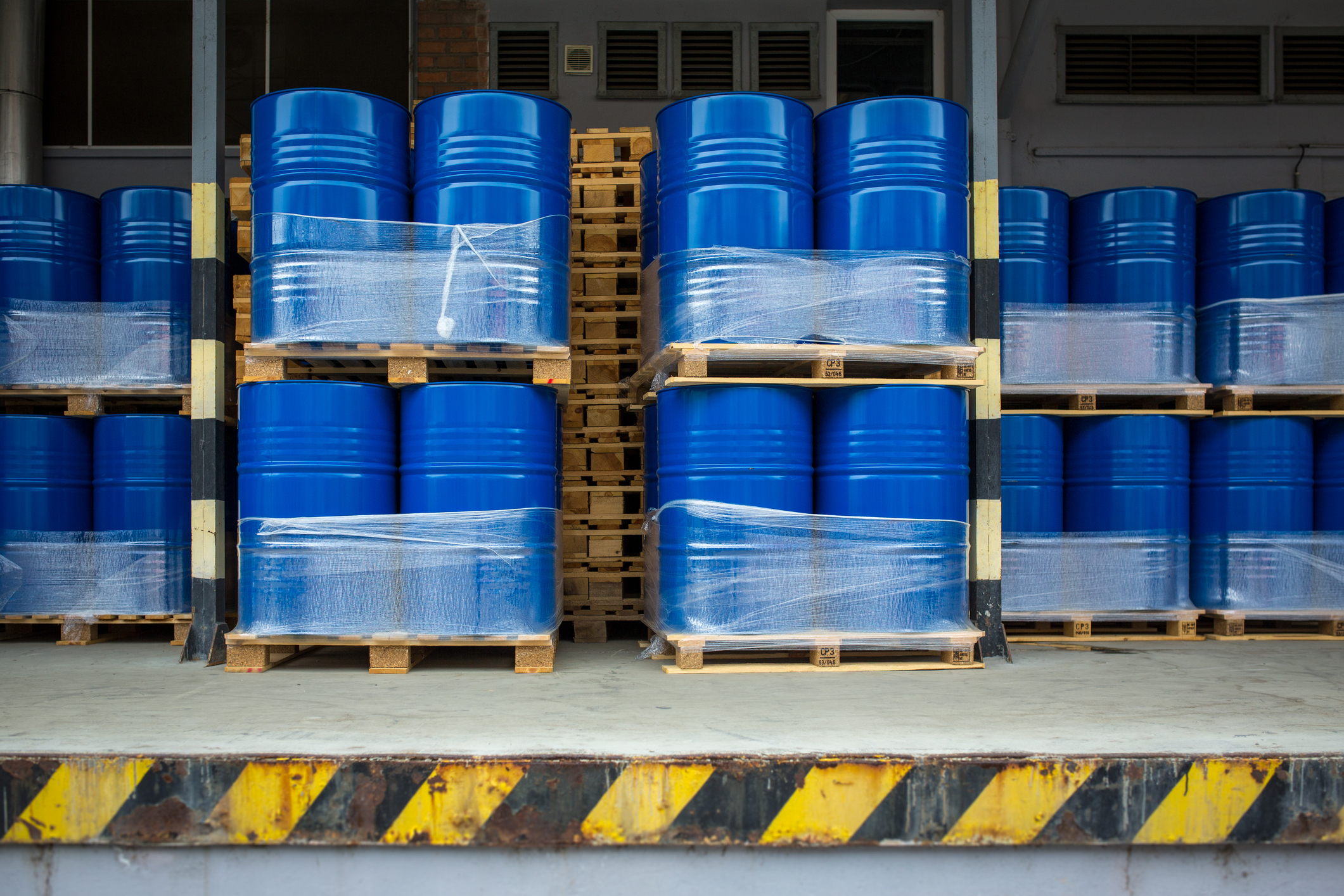 Large blue metal barrels stacked together in a factory.jpg Large blue metal barrels stacked together at a loading dock.