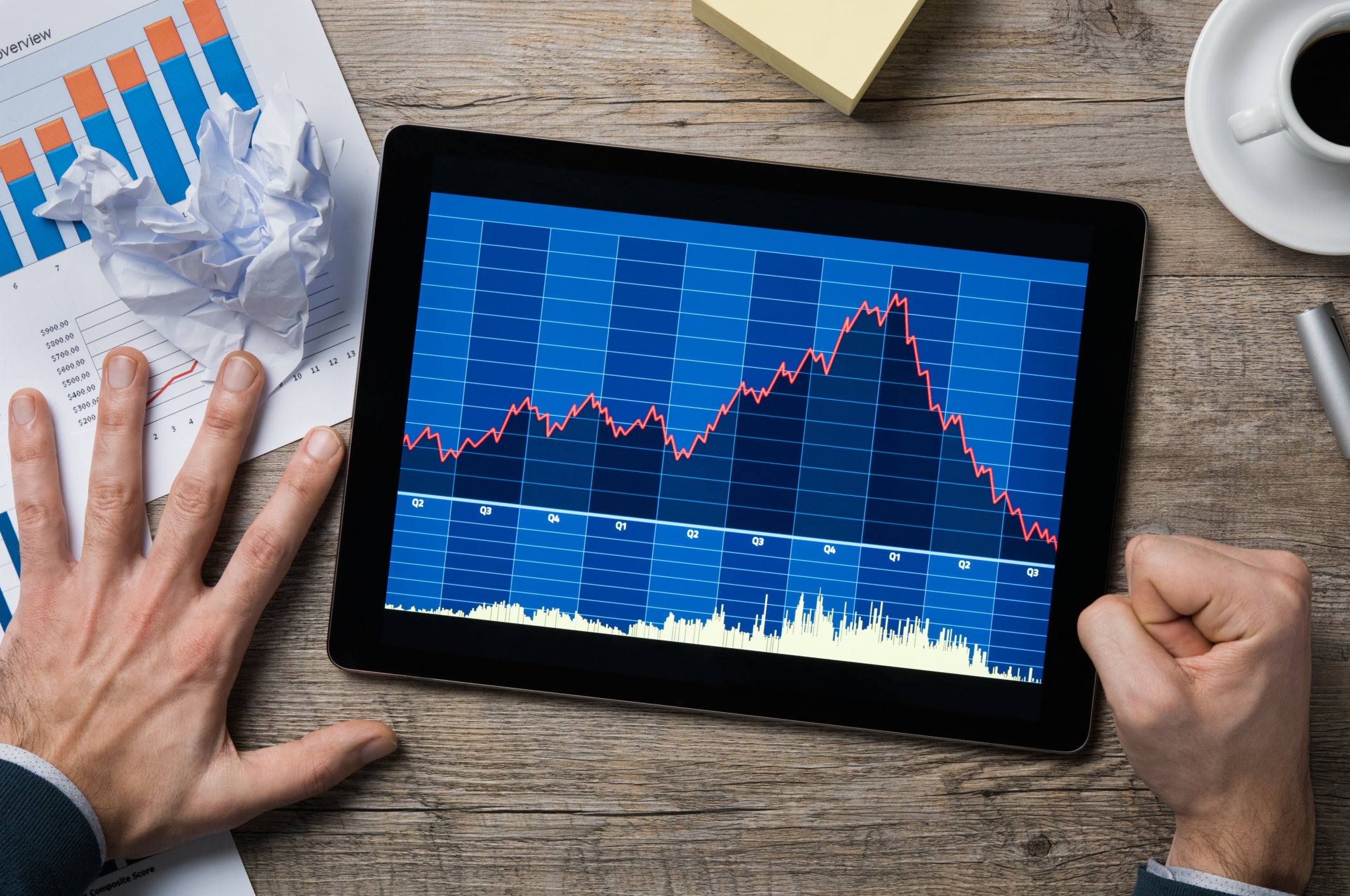 Man looking at declining share price chart on tablet and pounding fist on table stock broker market crash bear correction