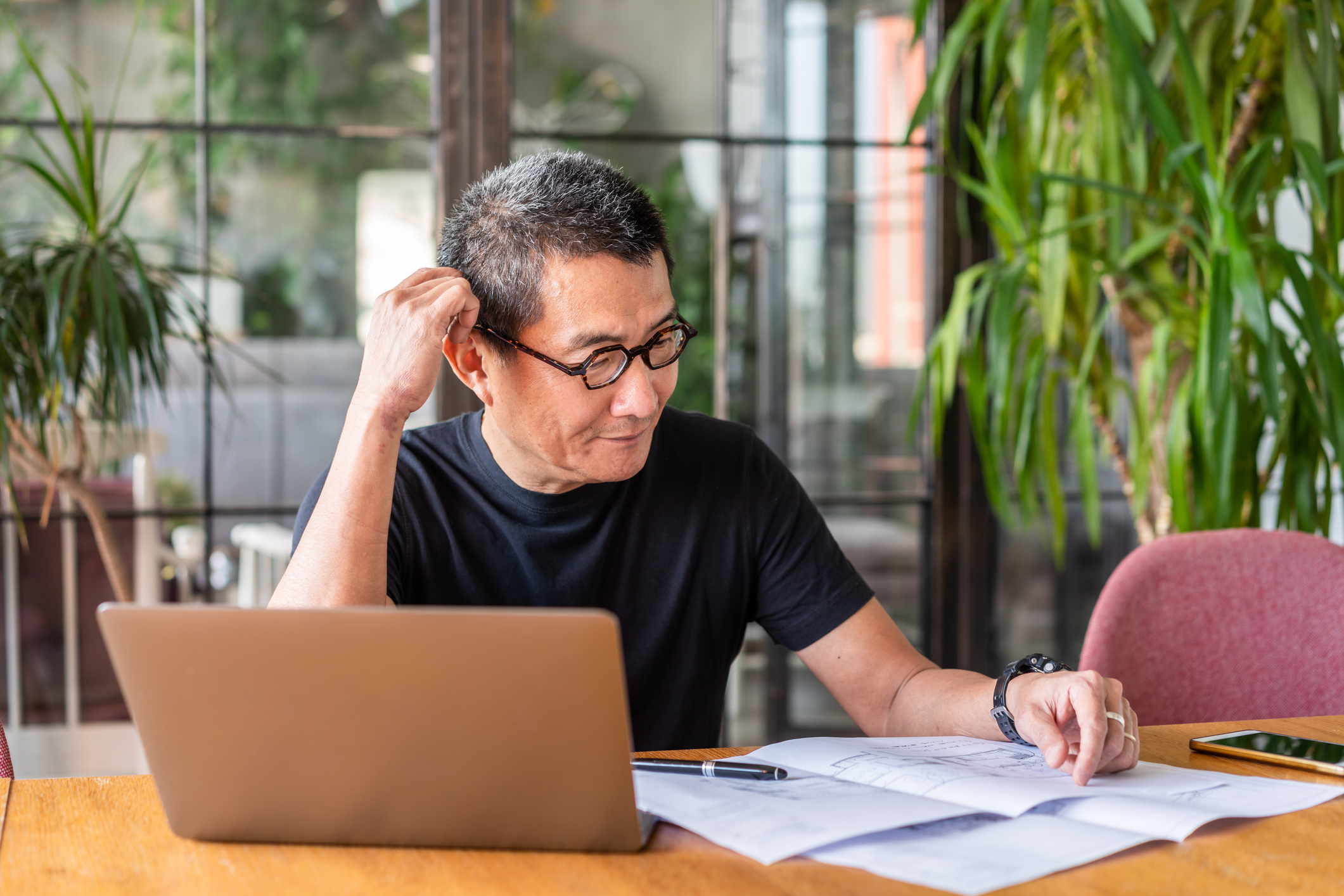 Person with laptop is looking at documents and thinking. Person with laptop is looking at documents and thinking.