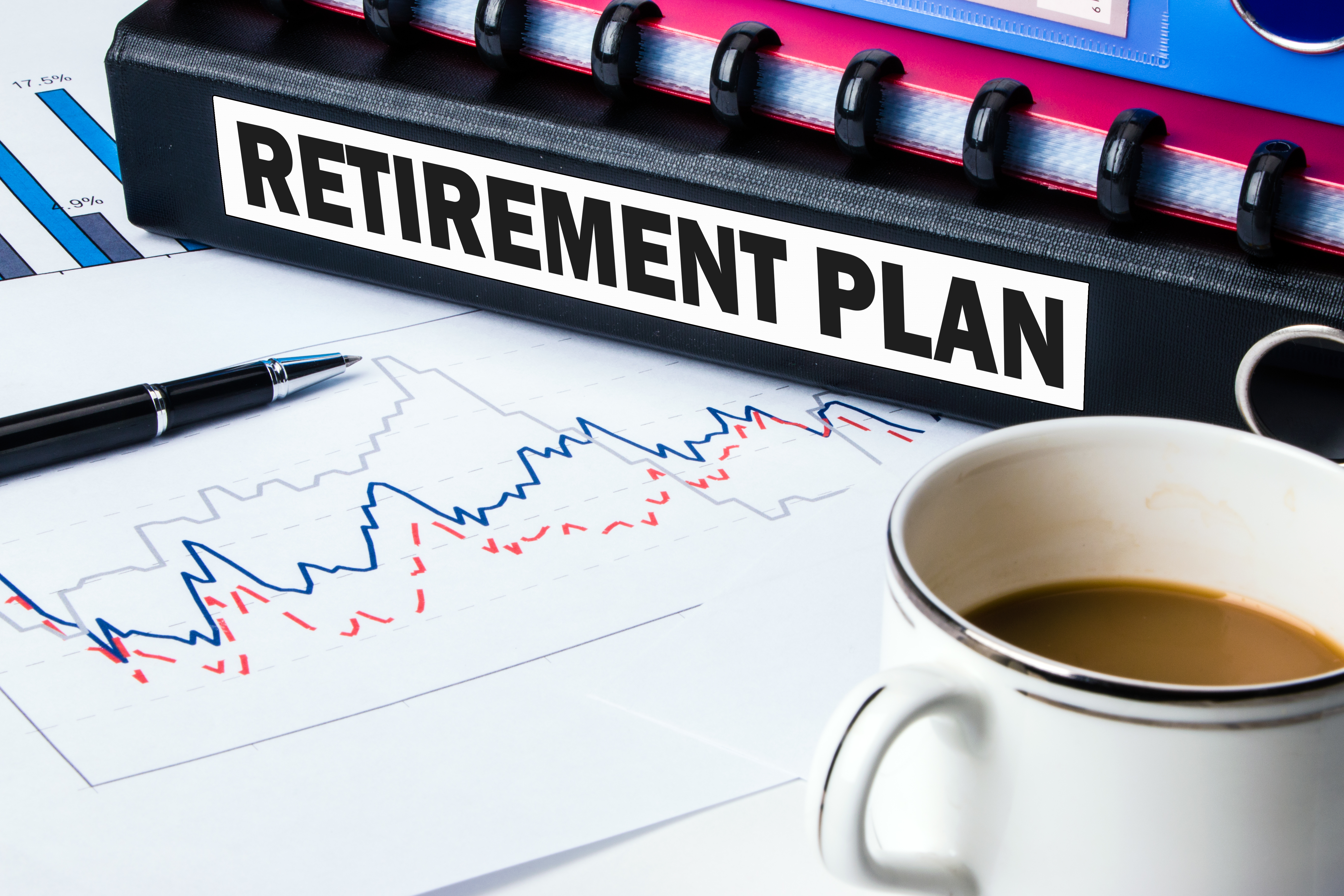 Retirement Plan folder with charts coffee and pen Retirement Plan folder sitting atop charts and next to coffee and a pen.